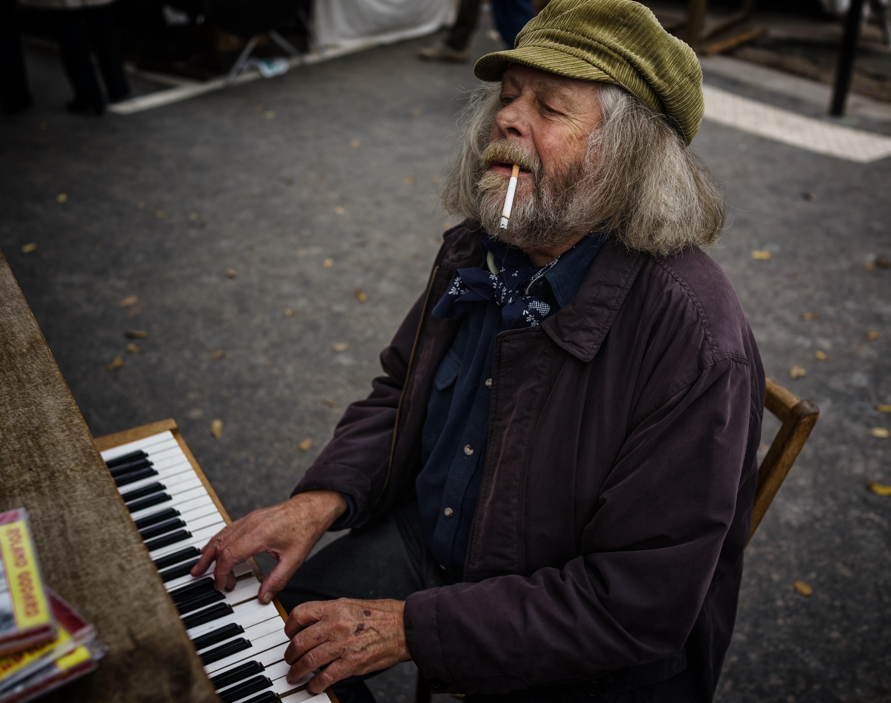 Eldre mann spiller på et piano ute