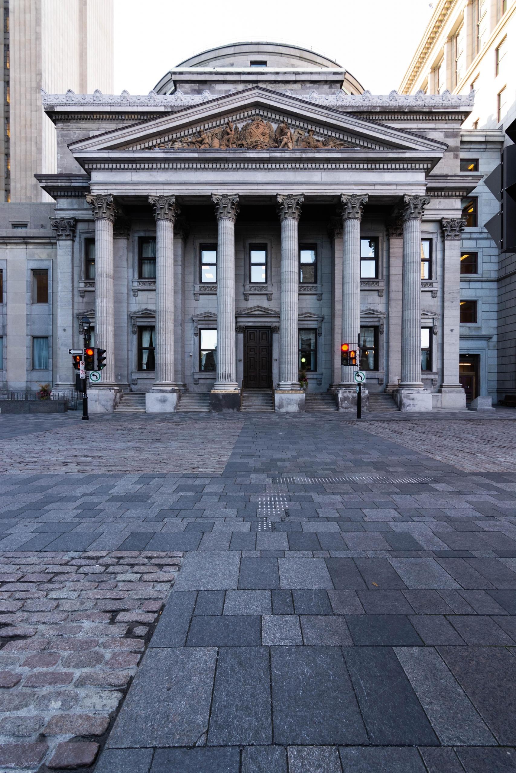 Grå bygning med søyler ved hellelagt plass