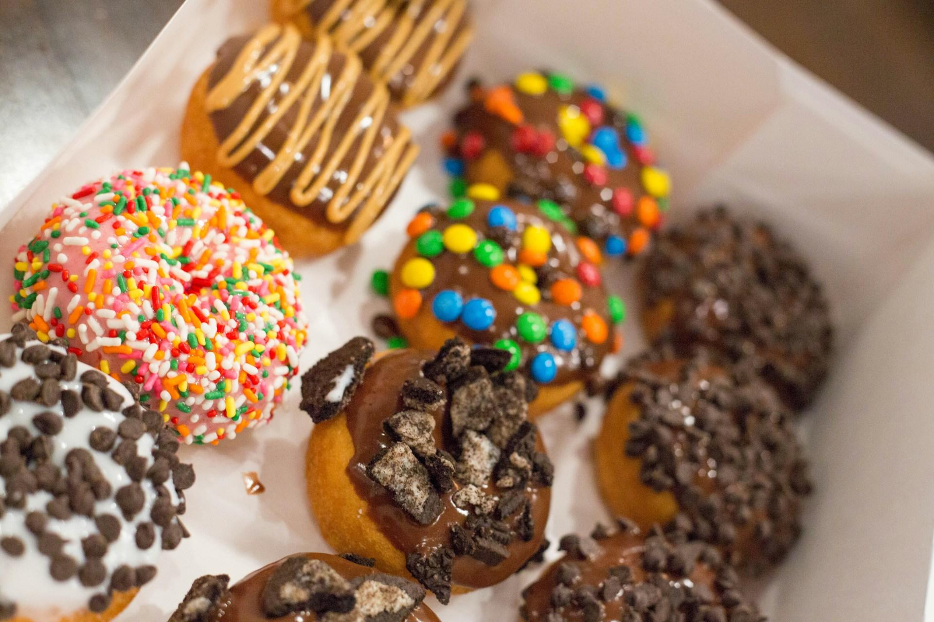 Dekorerte donuts med ulik pynt i pappeske.