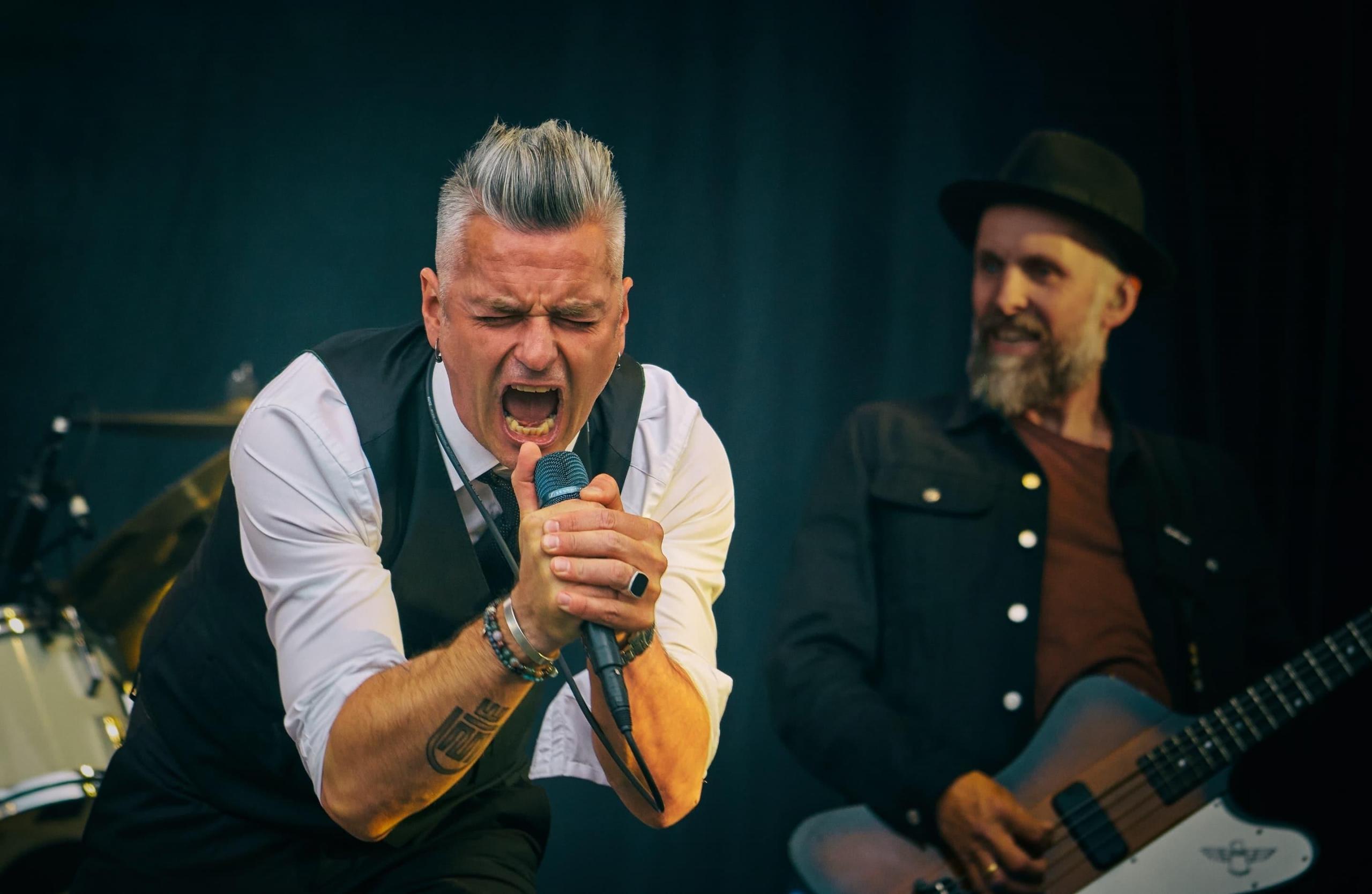Janove Ottesen synger engasjert i en mikrofon på konsert
