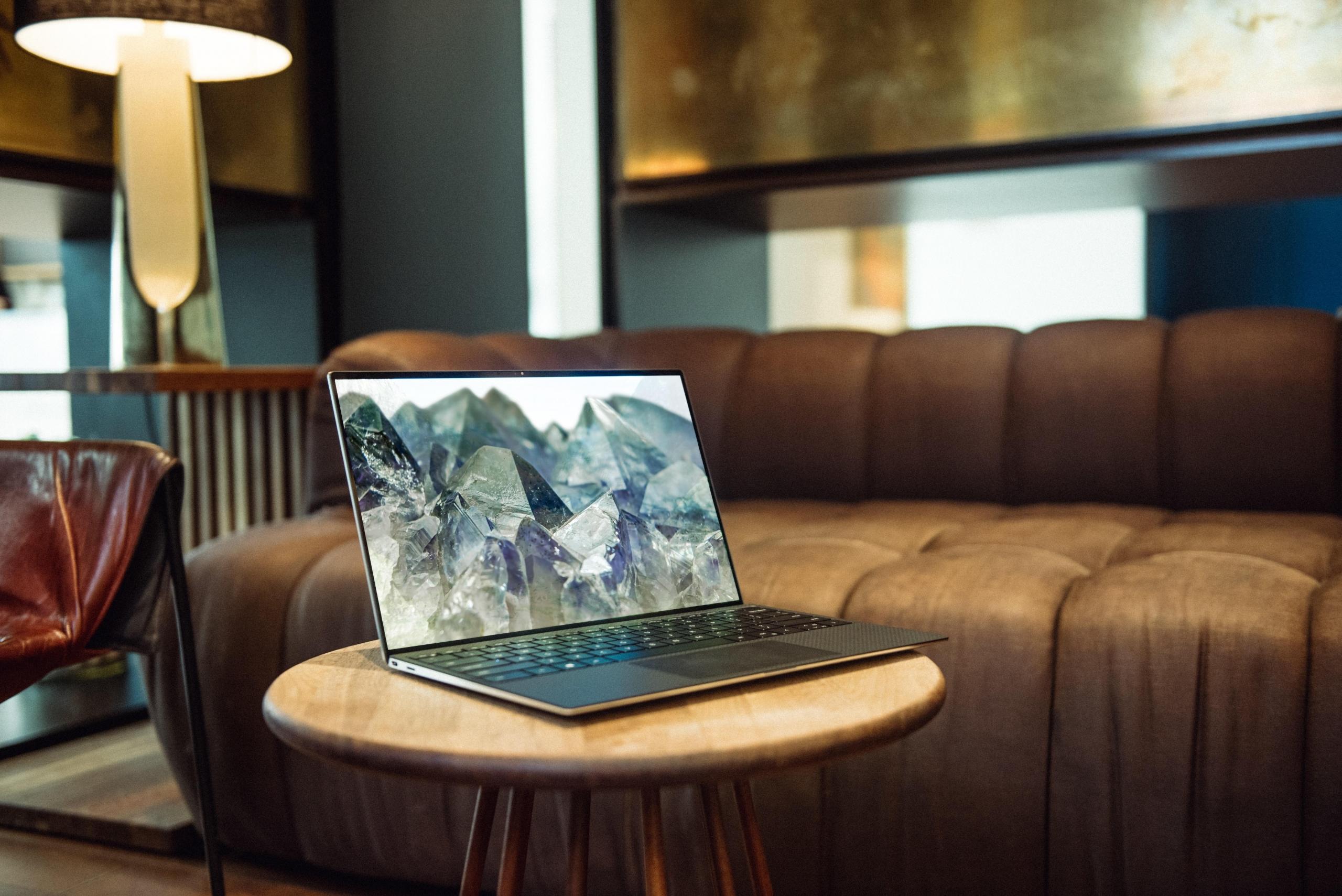 en laptop står på et lite stuebord foran en brun skinnsofa