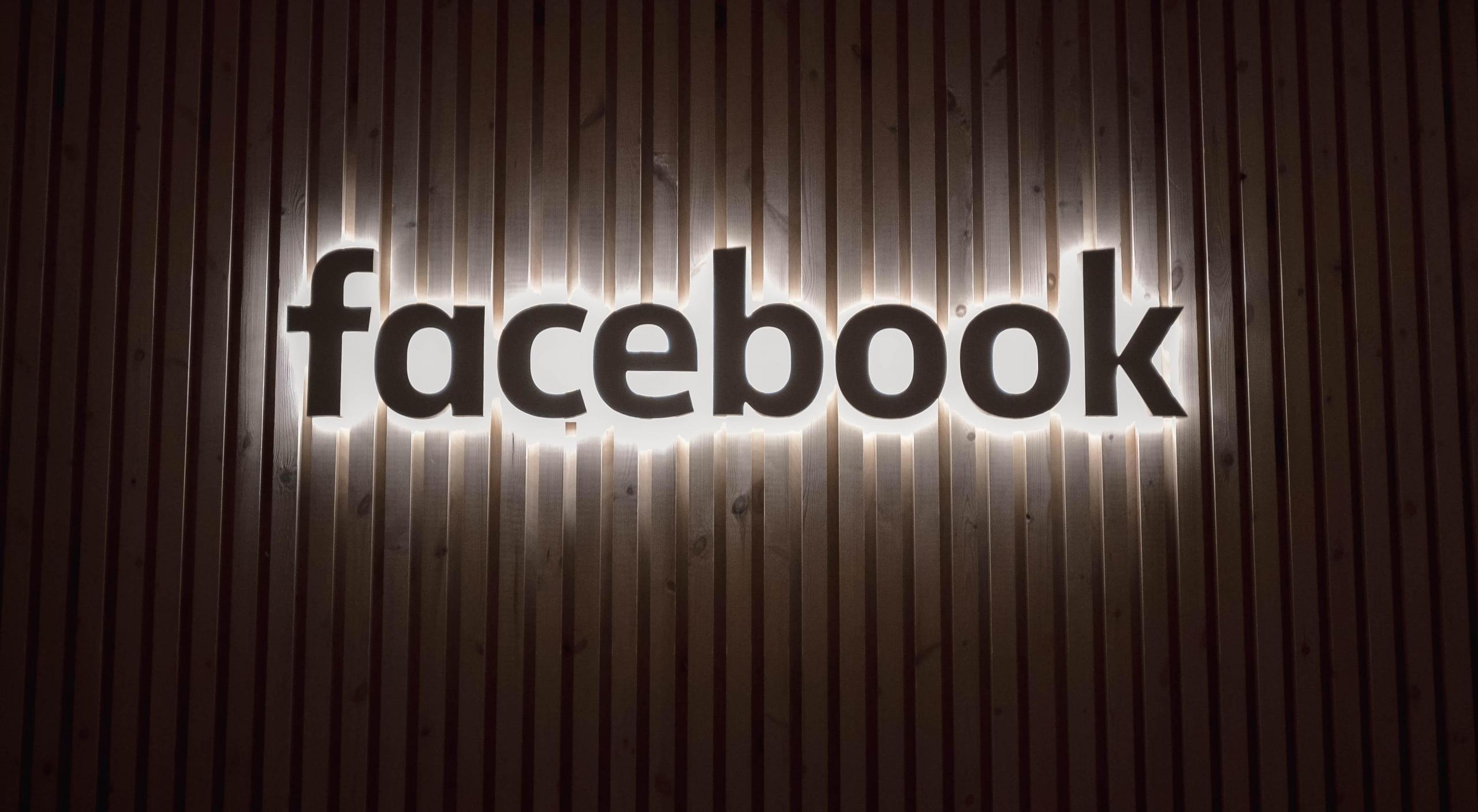 et lysende facebook-skilt som henger på en moderne trevegg