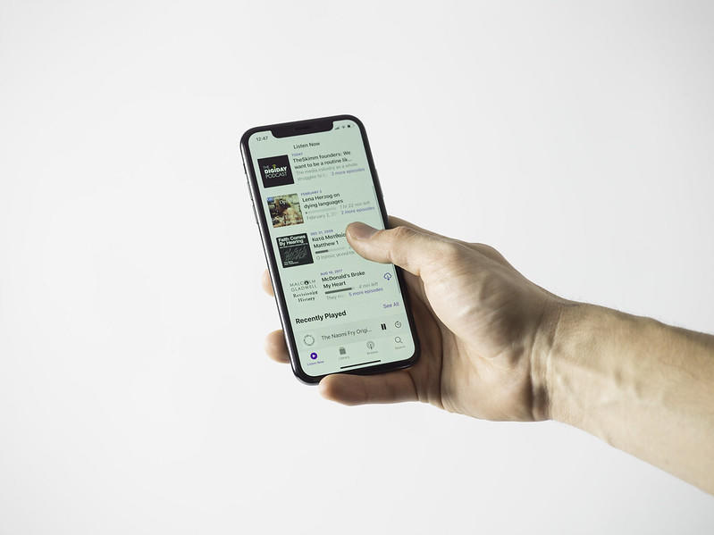 En person ser på tilgjengelige podkaster på mobilen.