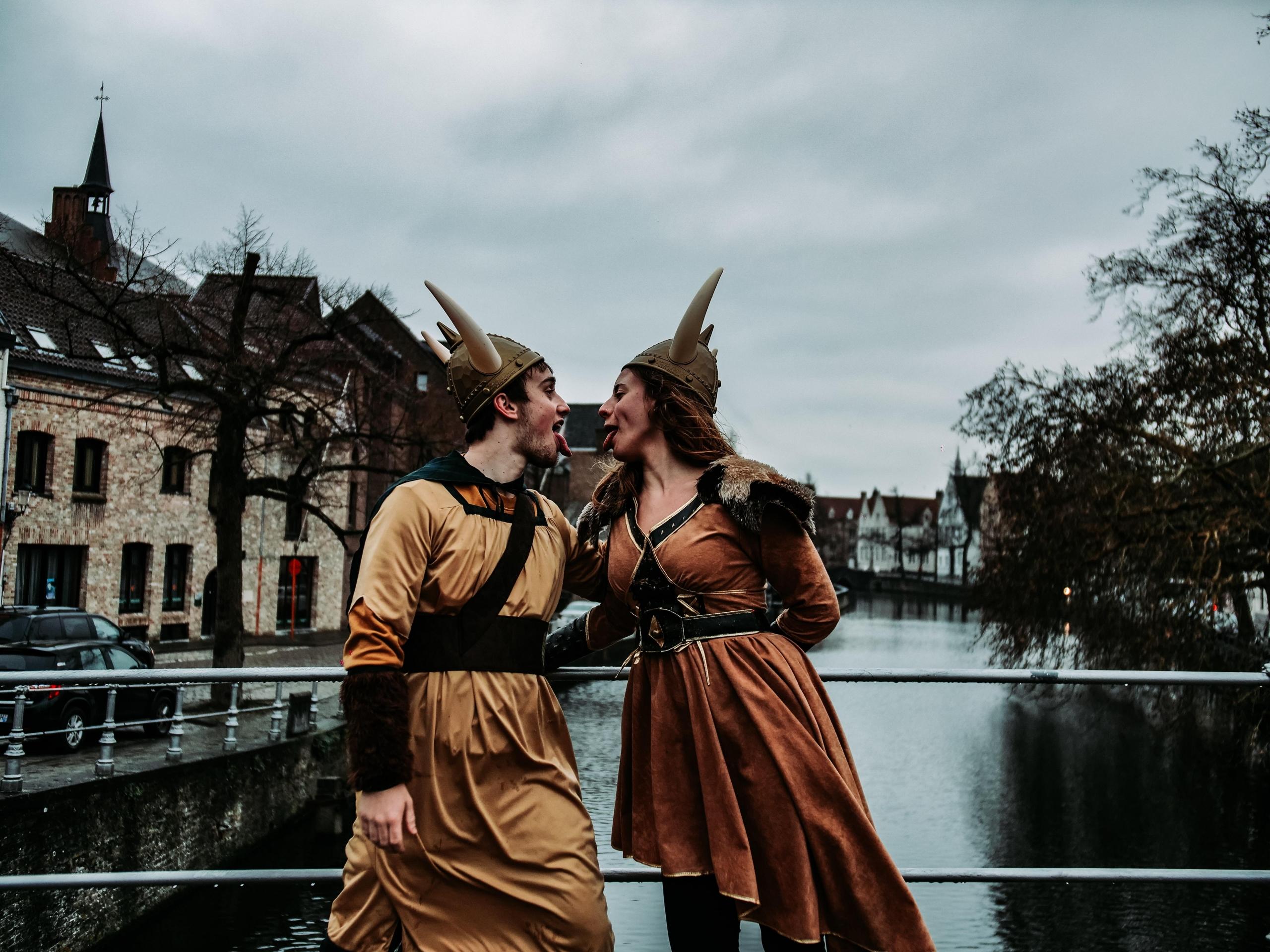 to personer rekker tunge til hverandre, de står på en bro og er kledd i vikingkostymer