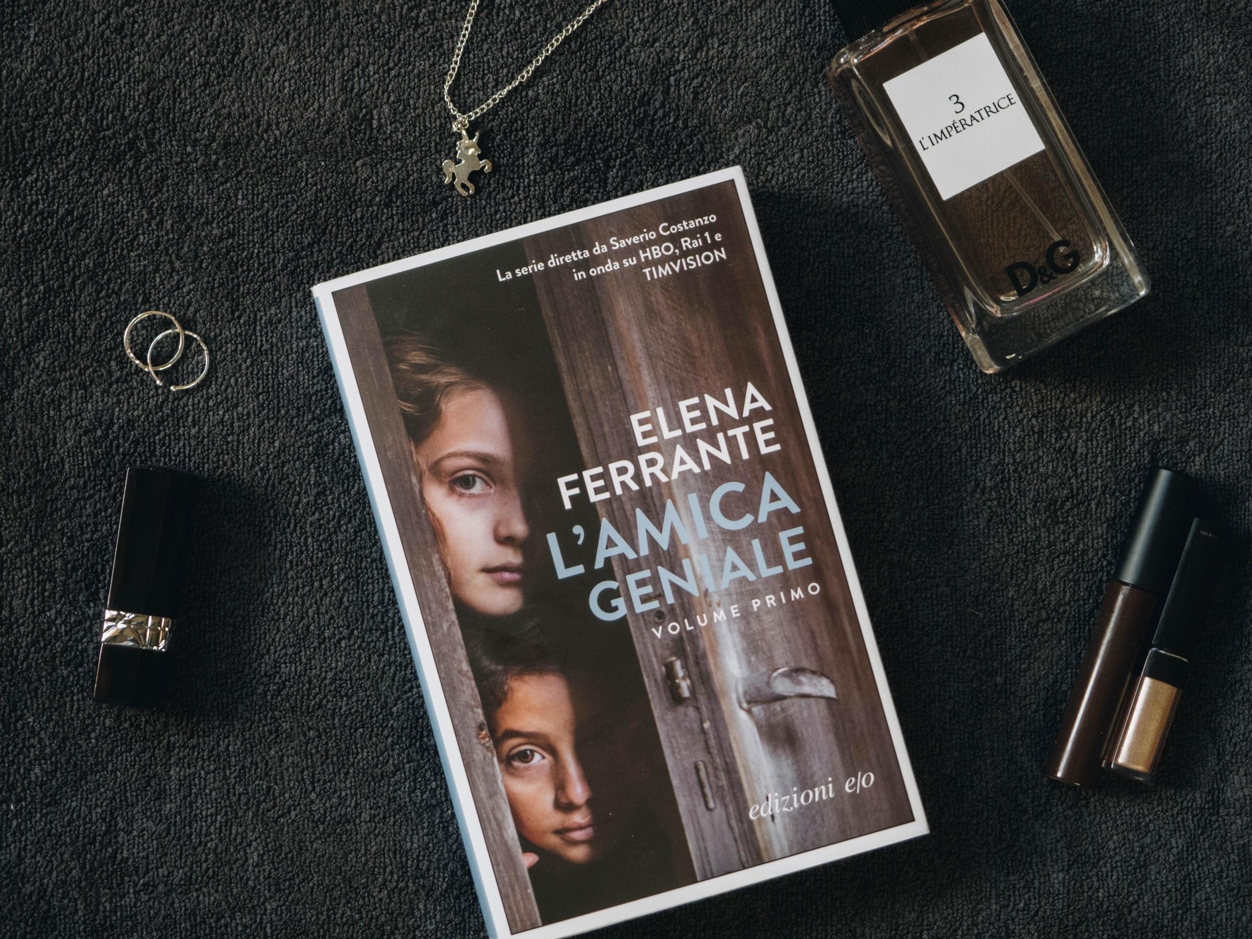 bilde ovenfra av elena ferrante-bok på italiensk, i tillegg til parfyme og diverse sminkeartikler