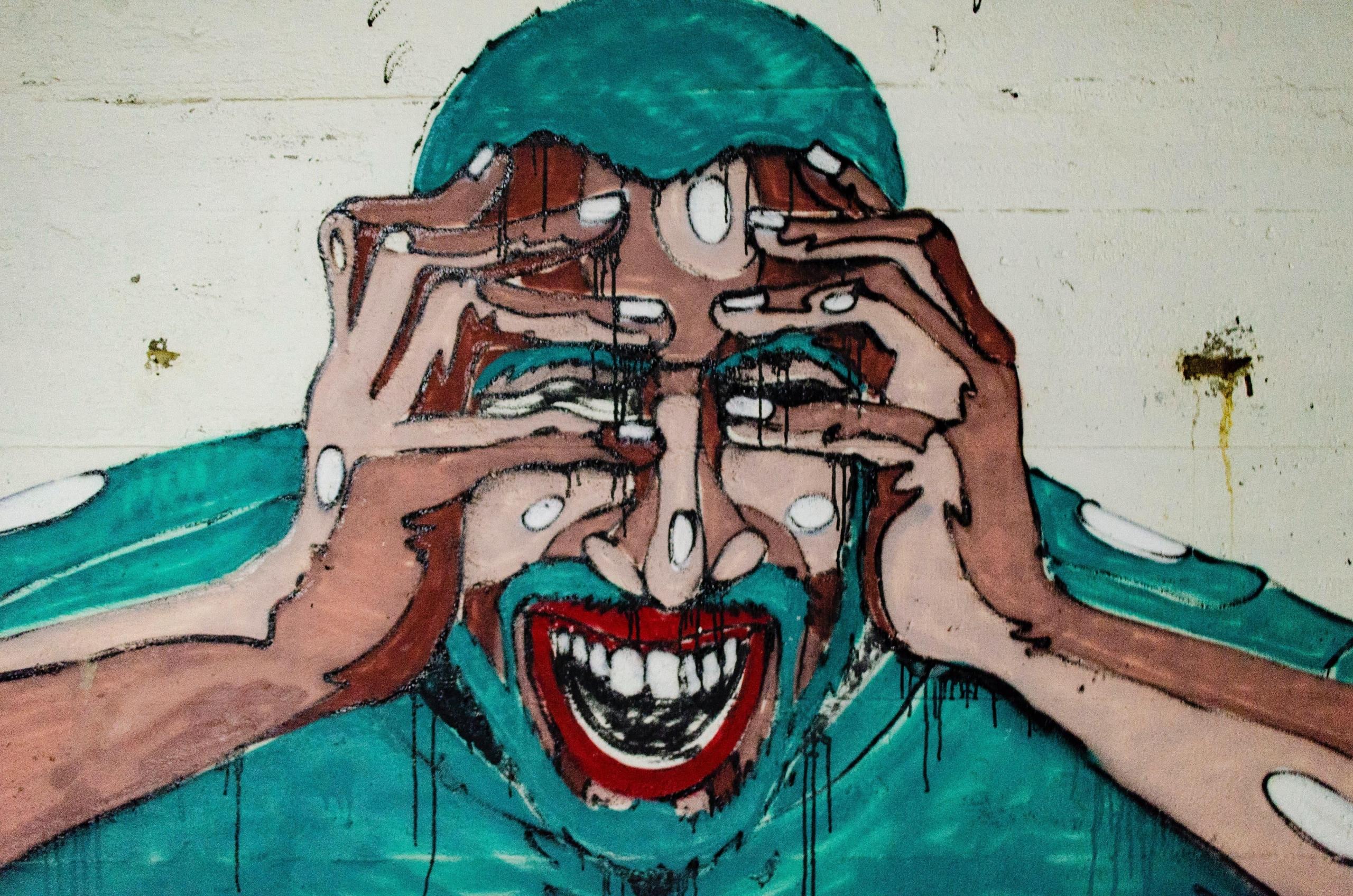 graffiti på beige vegg av en mann kledd i grønt som tar seg til hodet og tilsynelatende skriker