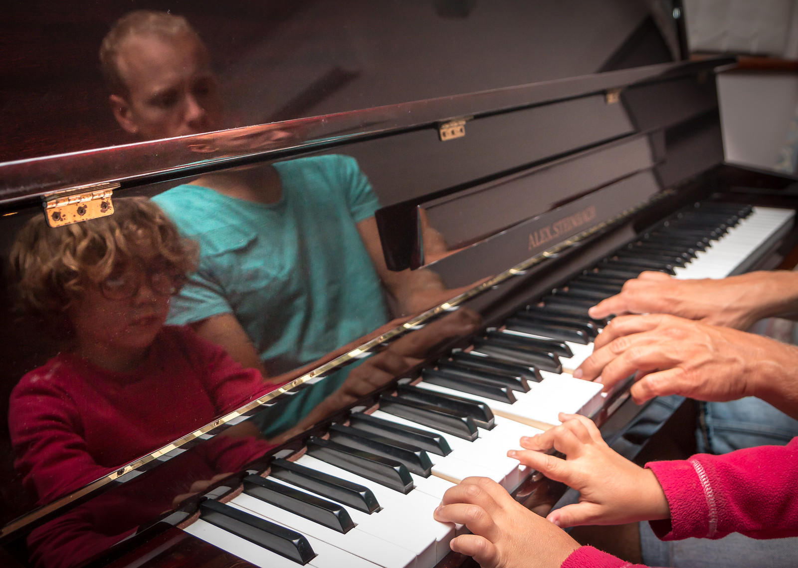 Et par barnehender og et par voksenhender på pianotangenter.