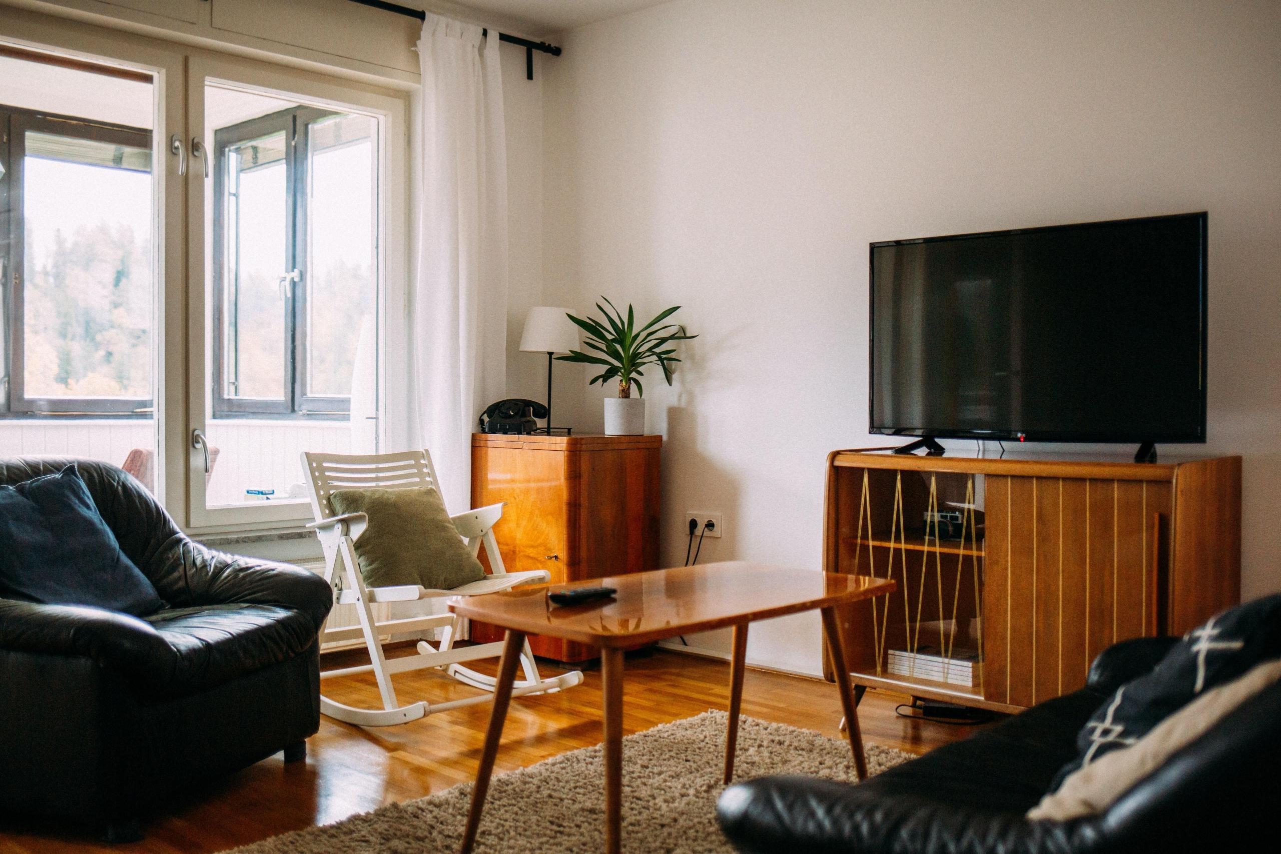 en lys stue med sofa, lenestol og tv