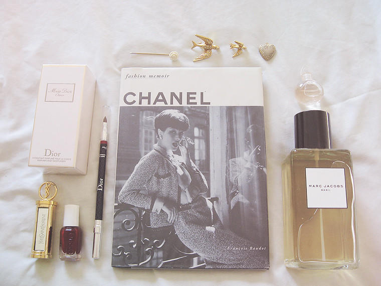 En bok med bile av Coco Chanel, en Marc Jacobs- og en Dior-parfyme samt sminke