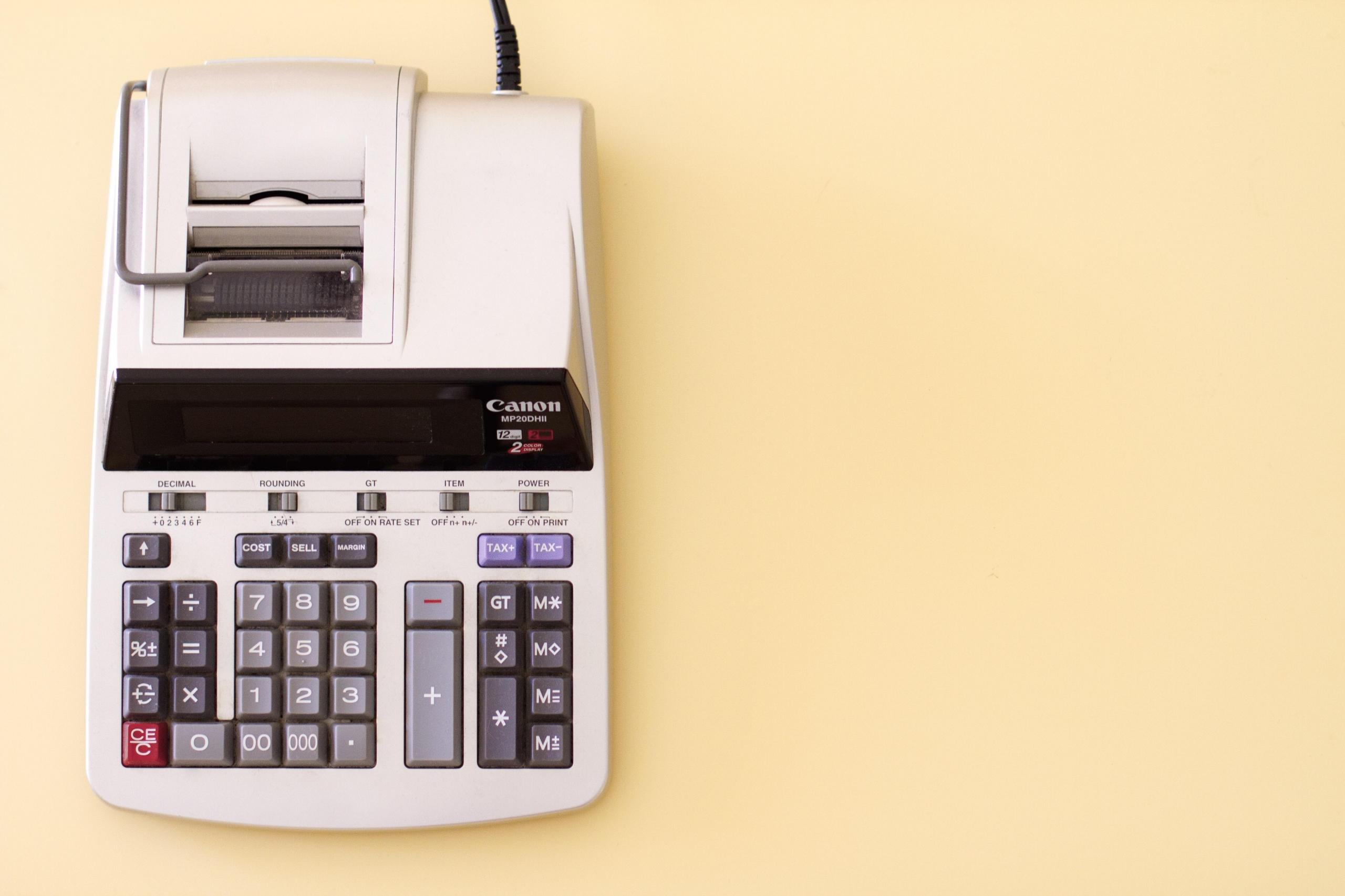 stor regnskapskalkulator på gul bakgrunn, inntrykket er relativt retro