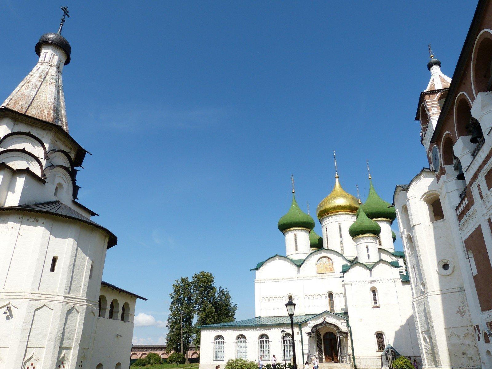 Hvite kirker med gyldne og grønne spirer i Suzdal i Russland