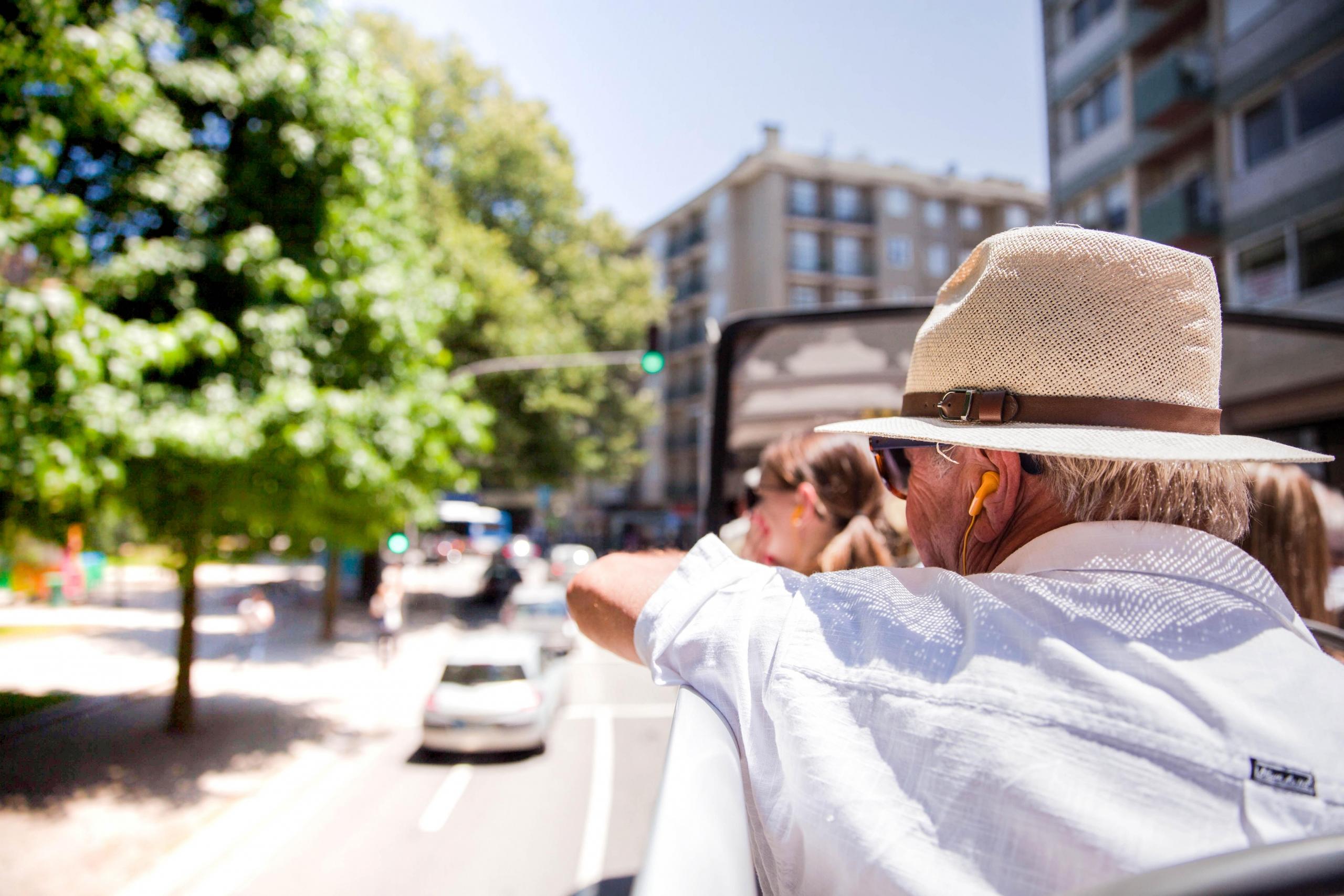 Turister i hatt ser utover byen fra en turistbuss.