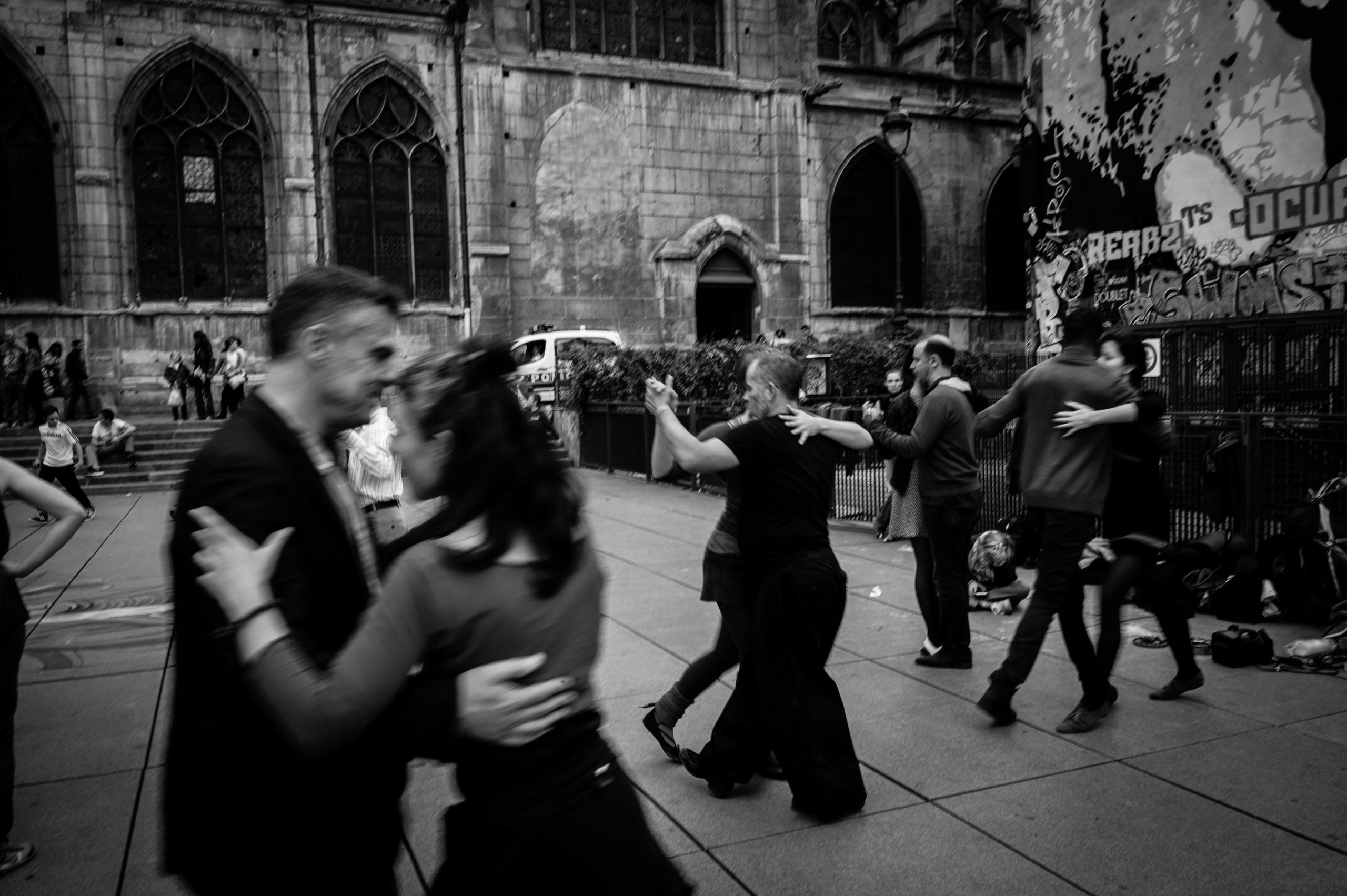 svart-hvitt-foto av flere par som danser tango på en åpen plass utendørs