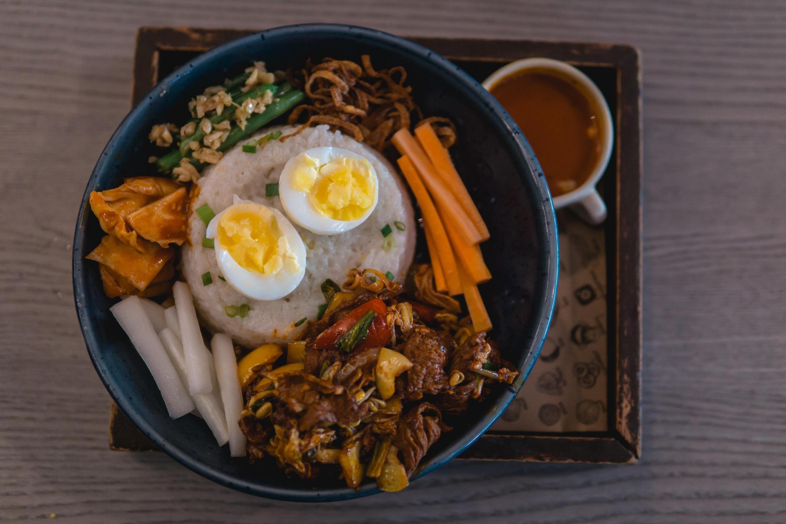 bibimbap med biff på tallerken, med kokt egg og grønnsaker