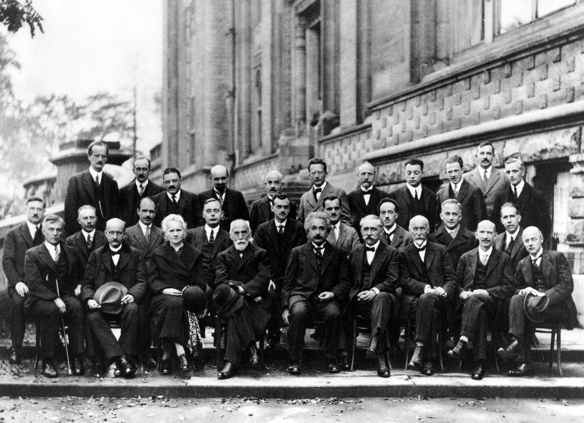 Svart-hvitt-bilde fra en forskerkonferanse. På første rad, Marie Curie og Ambert Einstein.