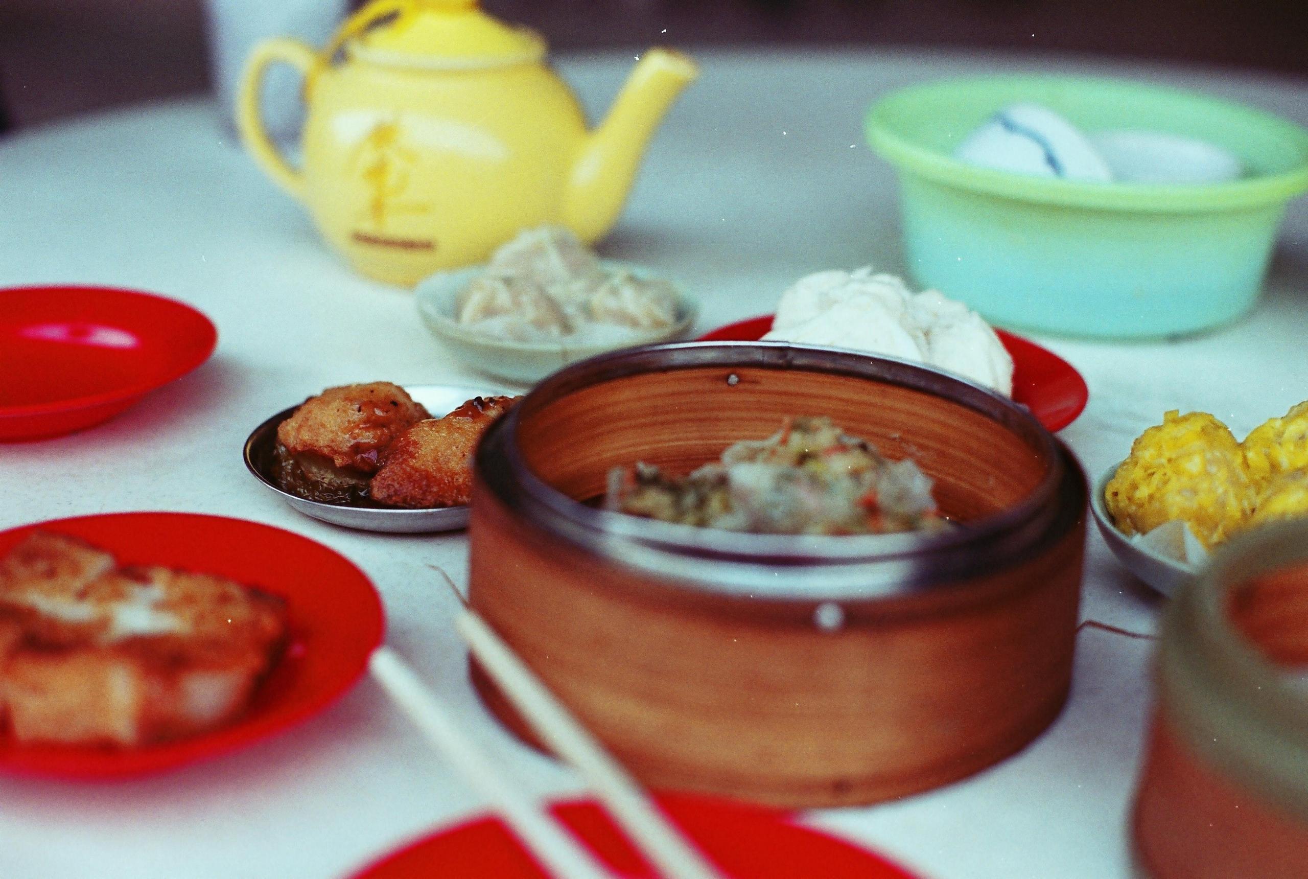 dim sum servert på små fat, noe fritert, noe dampet, en tekanne står i bakgrunnen