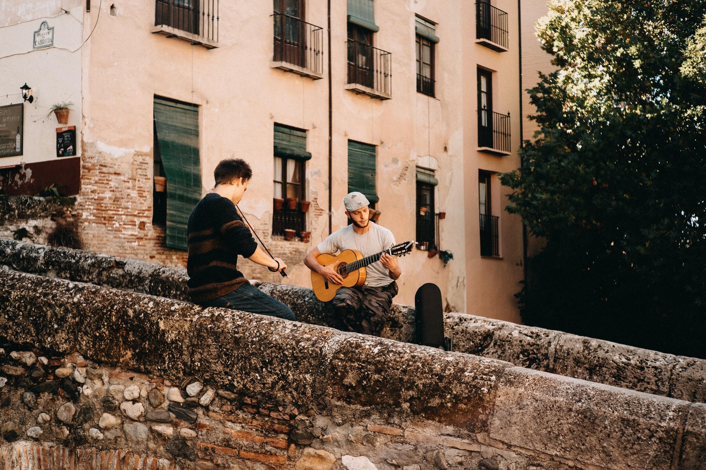 En fiolin og gitarspiller spiller musikk ute