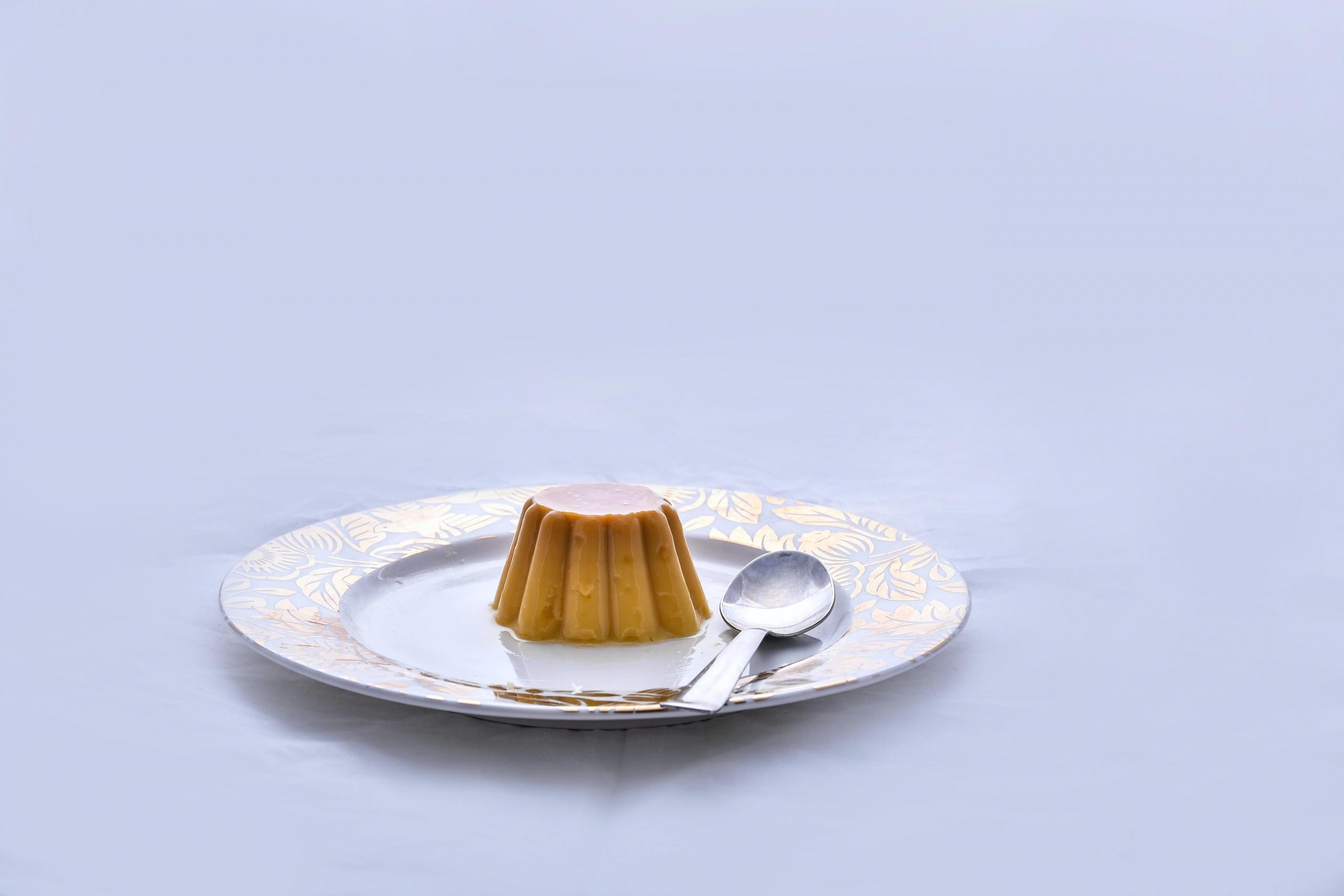 Karamellpudding og skje på tallerken.