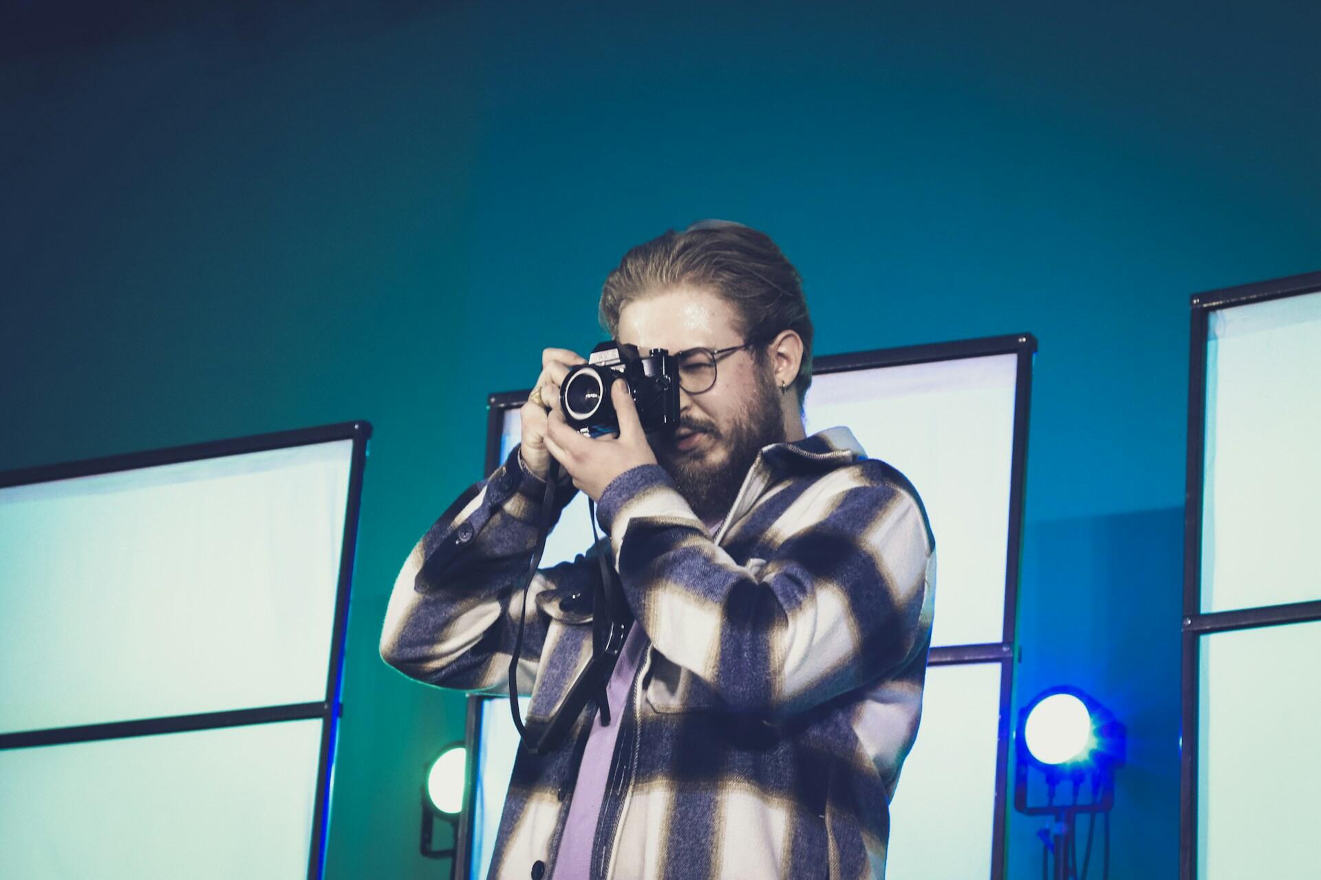 Ung mann fotograferer med speilreflekskamera i studio med blått lys