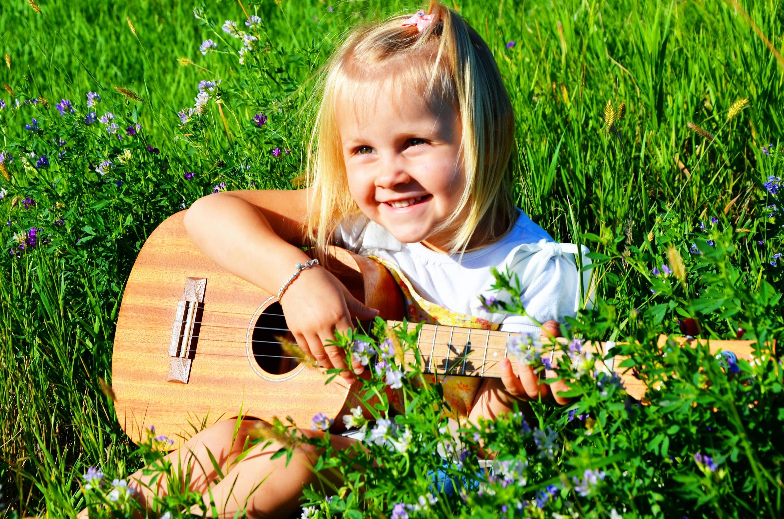 Småjenter i blomstereng spille gitar.