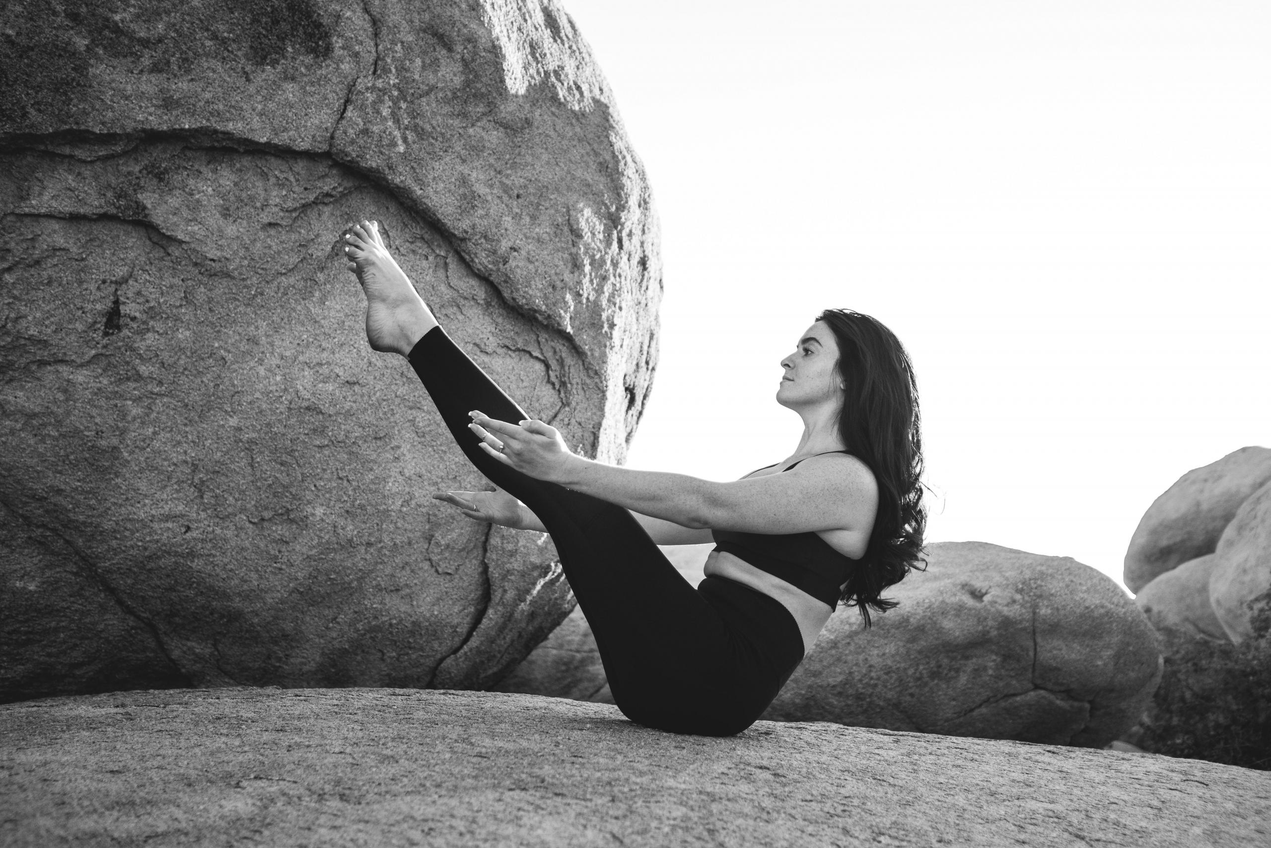 svart-hvitt-foto av en kvinne som gjør yoga på et berg med steiner i bakgrunnen