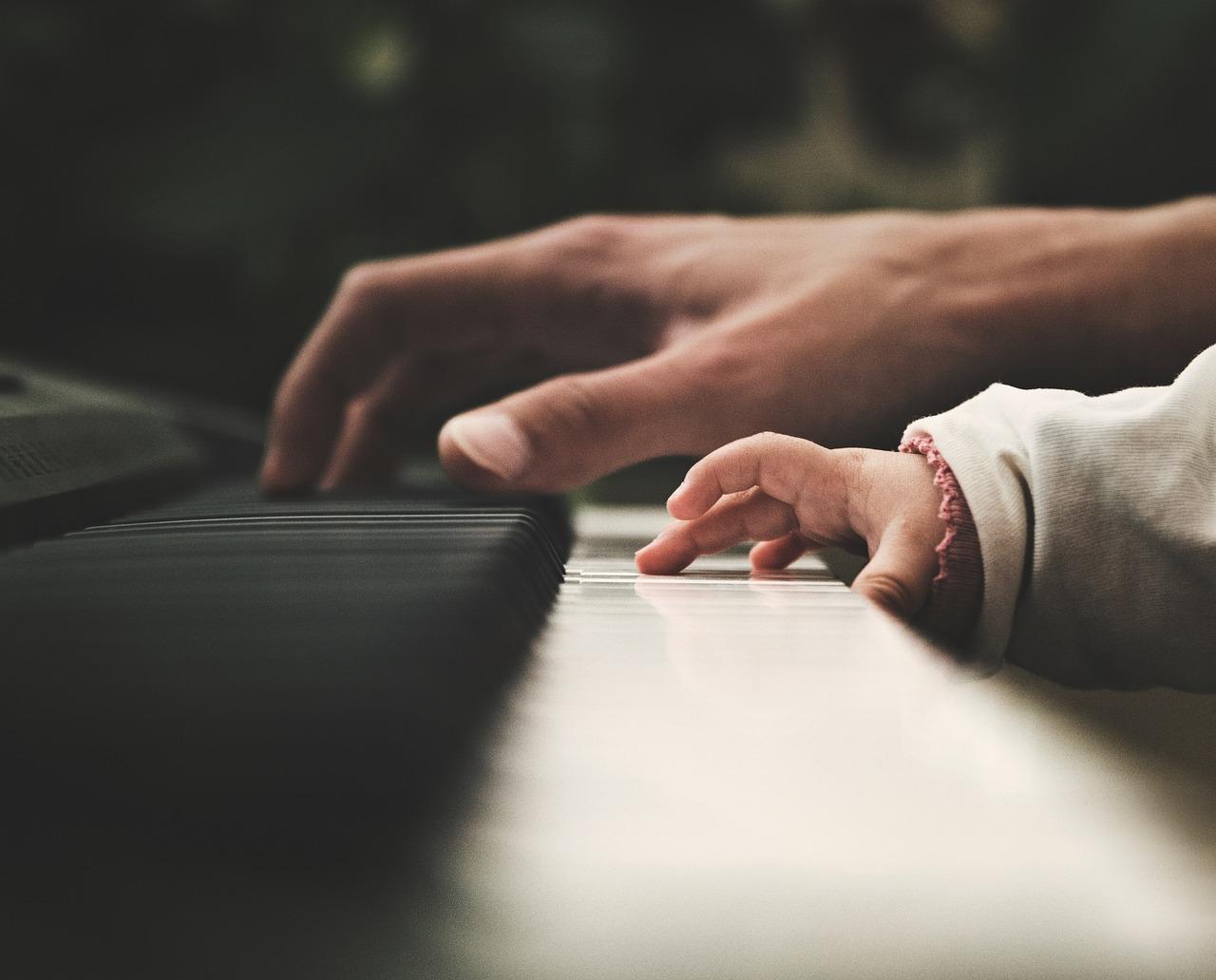 Voksen og barn spiller piano sammen