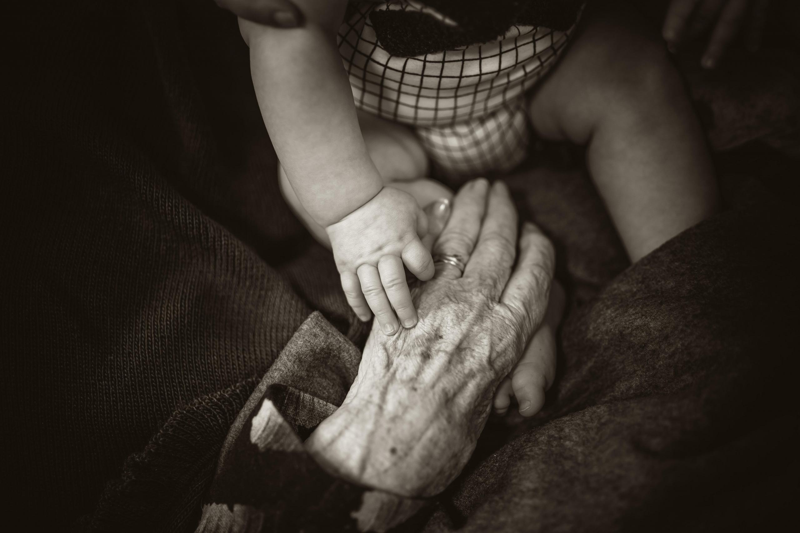 Eldre hender holder om babyhender.
