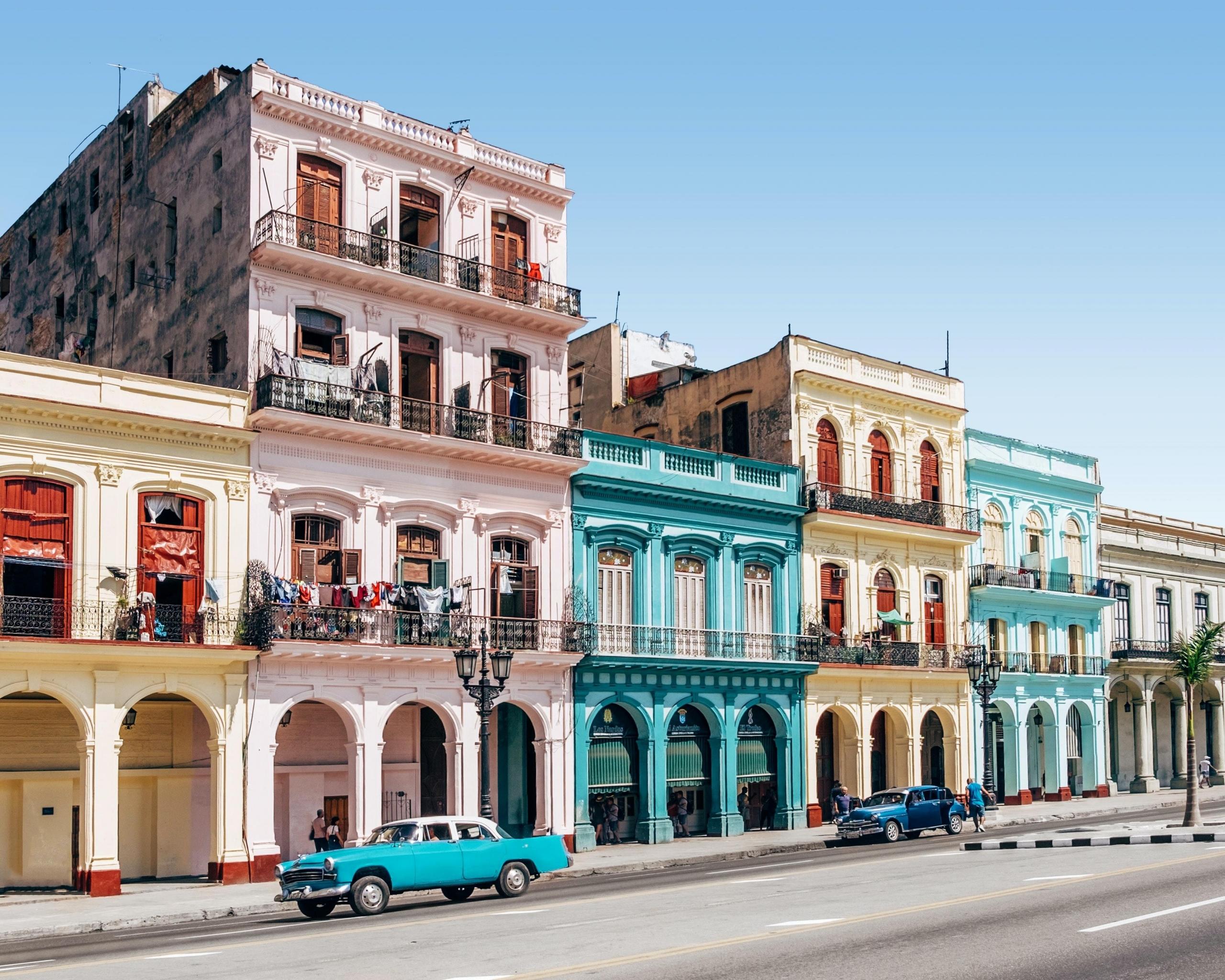 fargerike bygninger og biler langs en gate på Cuba, himmelen er knallblå
