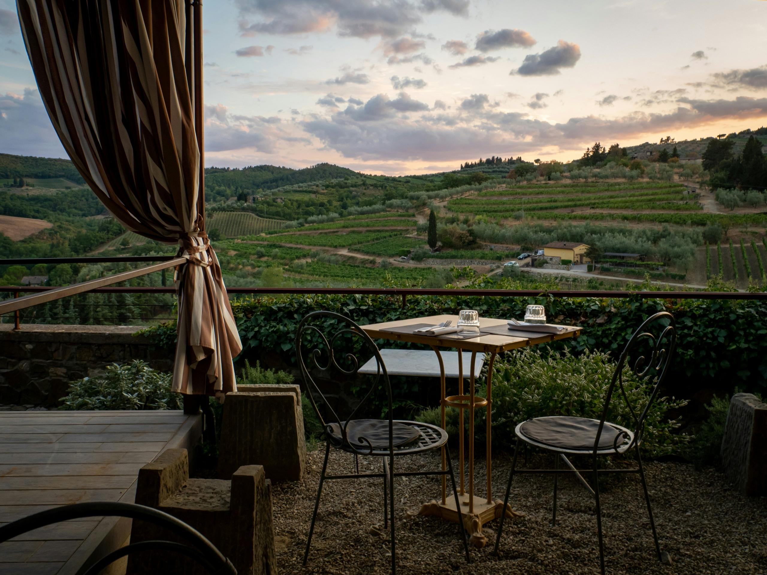 Et bord og stoler på en terrasse med utsikt over vinåkre i Italia.