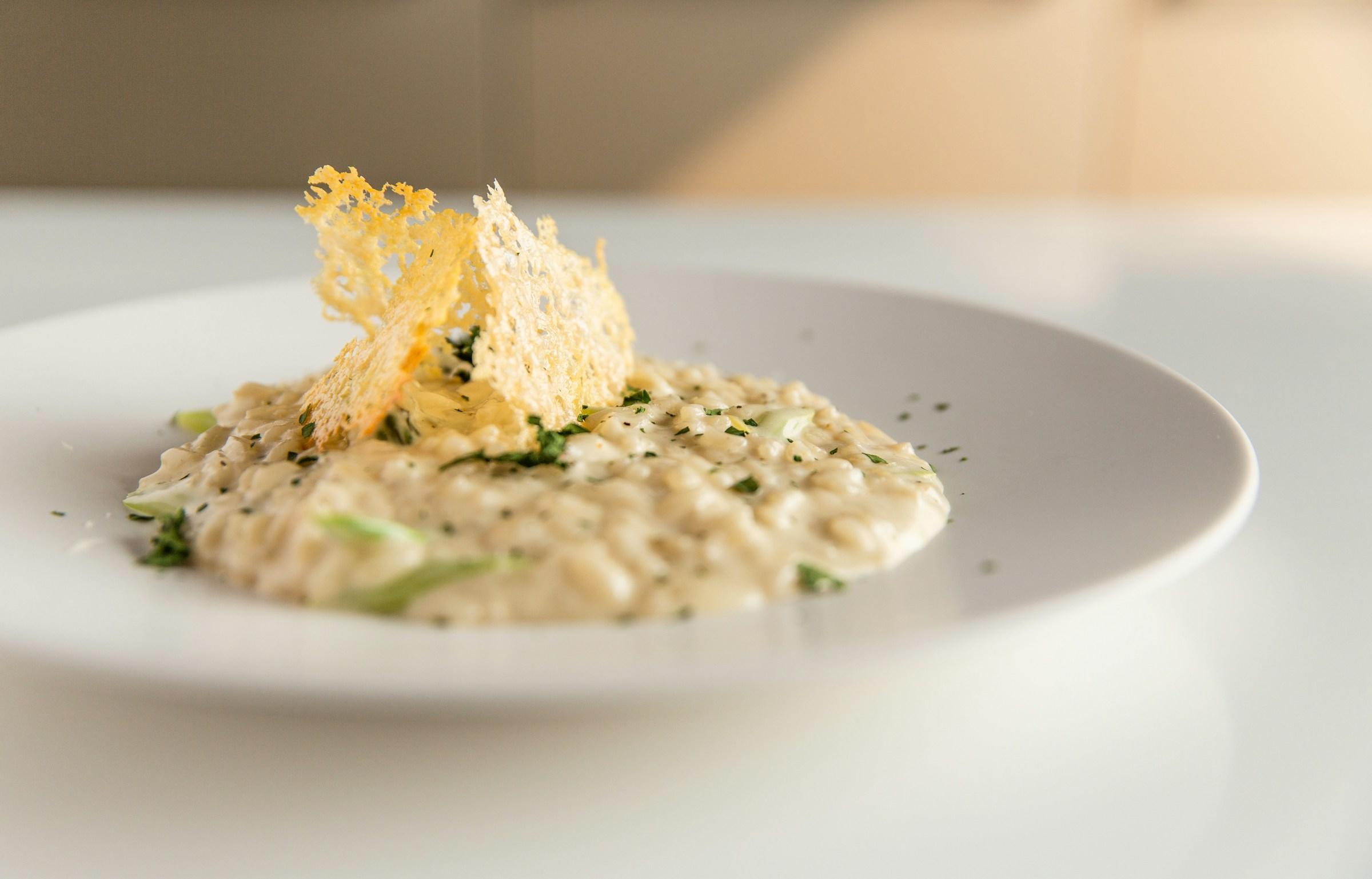 En hvit tallerken med risotto på et hvitt bord. 