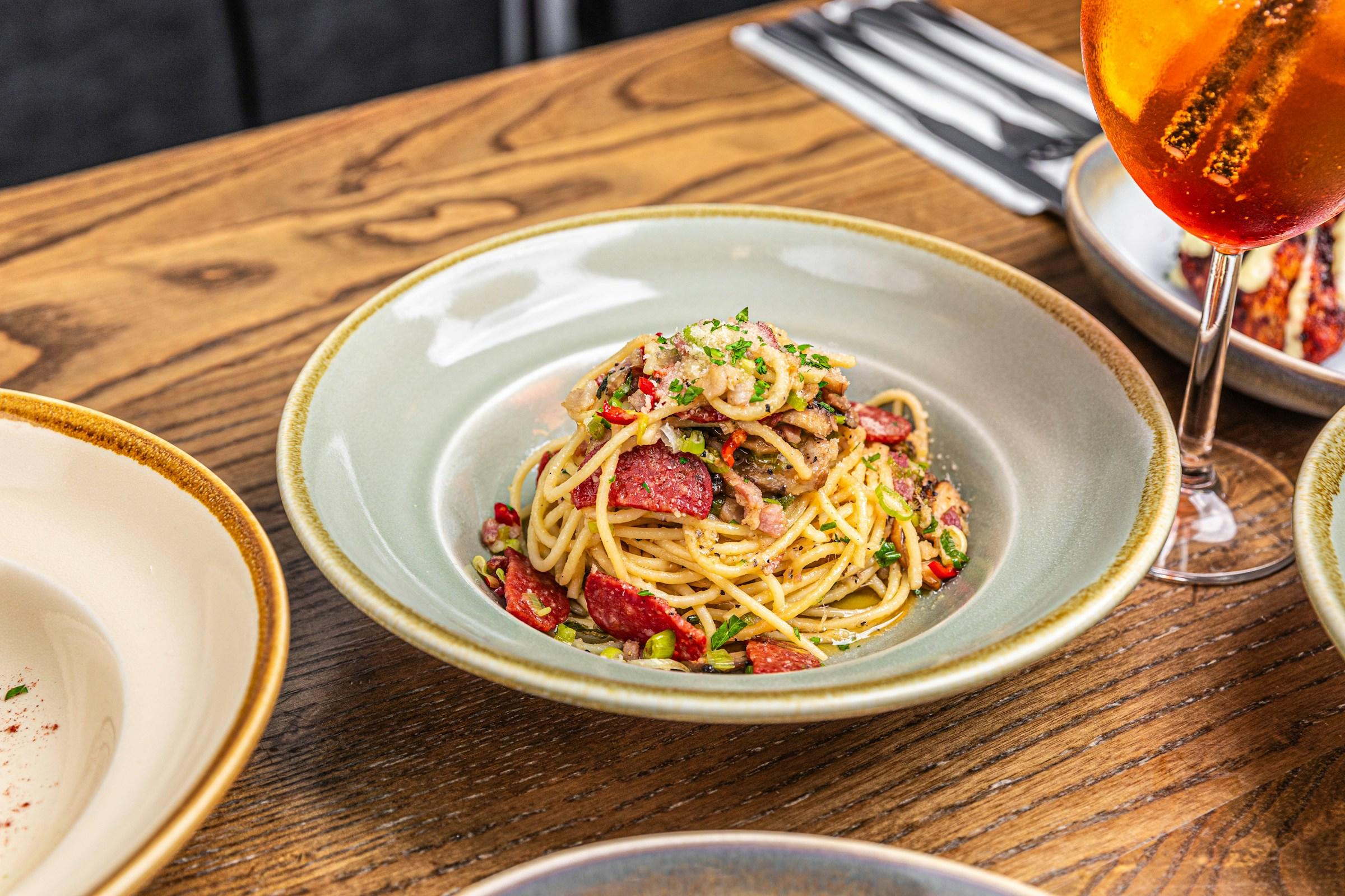 En tallerken med pasta på et bord, og et glass med drikke ved siden av.