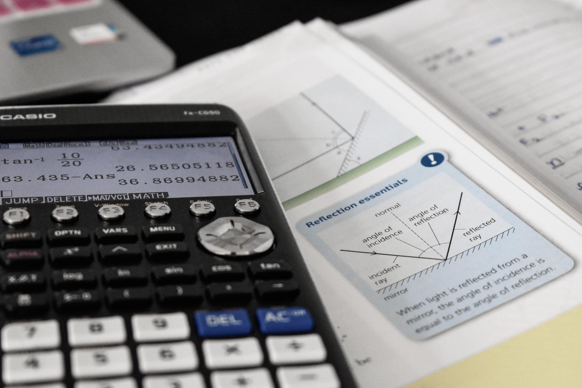 Nærbilde av avansert kalkulator og matematikkbok.