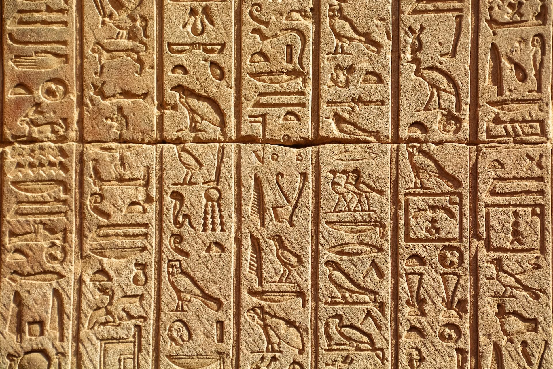 Hieroglyfer risset inn i steinvegg.
