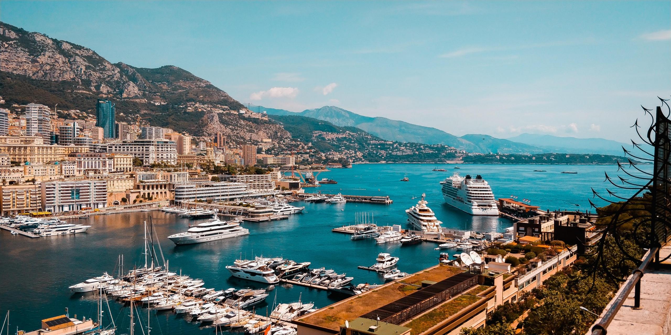 oversiktsbilde mot havnen i monte carlo, monaco, himmelen er blå, det ligger store skip og masse båter på vannet