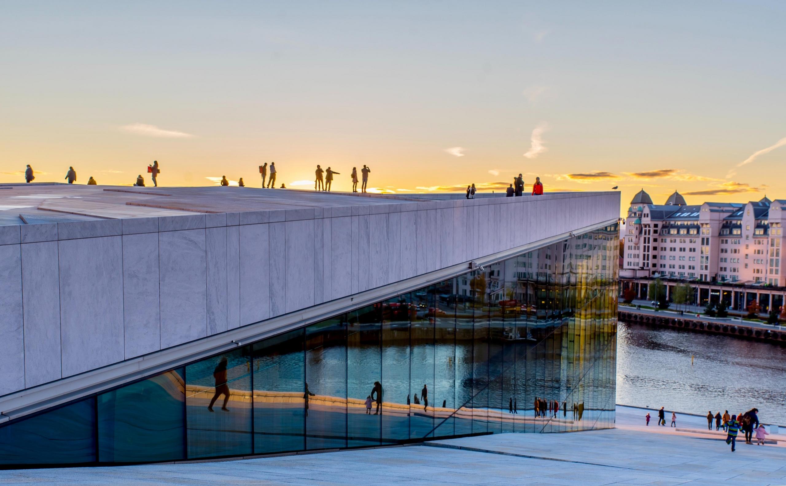 Operaen i Bjørvika med skikkelser på taket, sola har akkurat gått ned