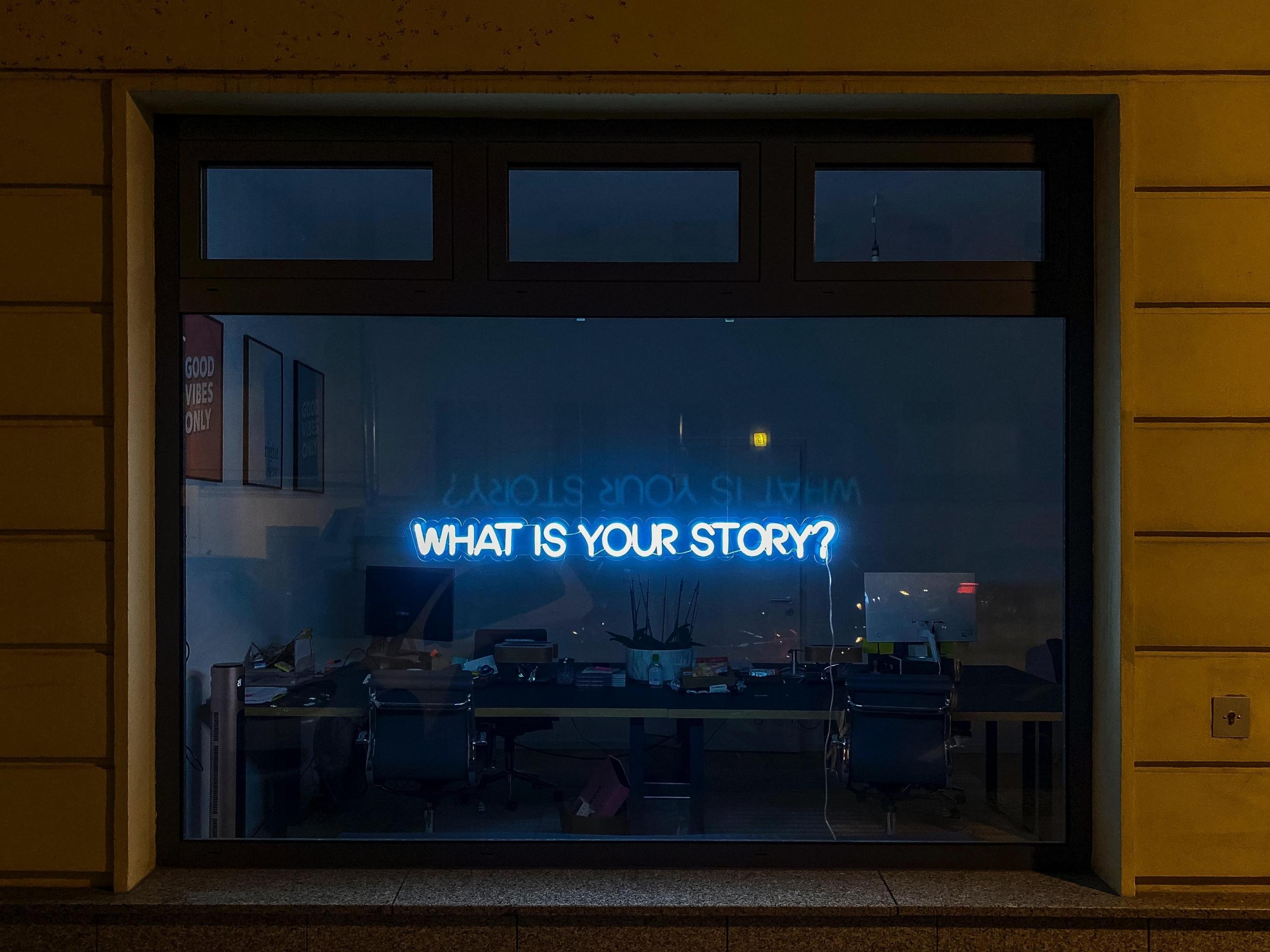 neonlys på vindu med teksten "what is your story?"