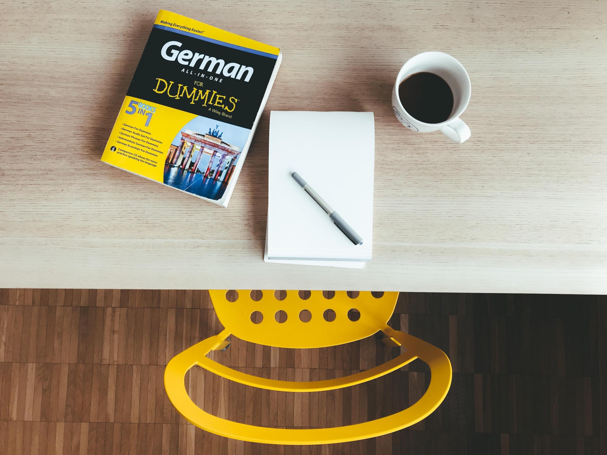 boka German for dummies ligger på et skrivebord sammen med en notatblokk, en penn og en kopp kaffe