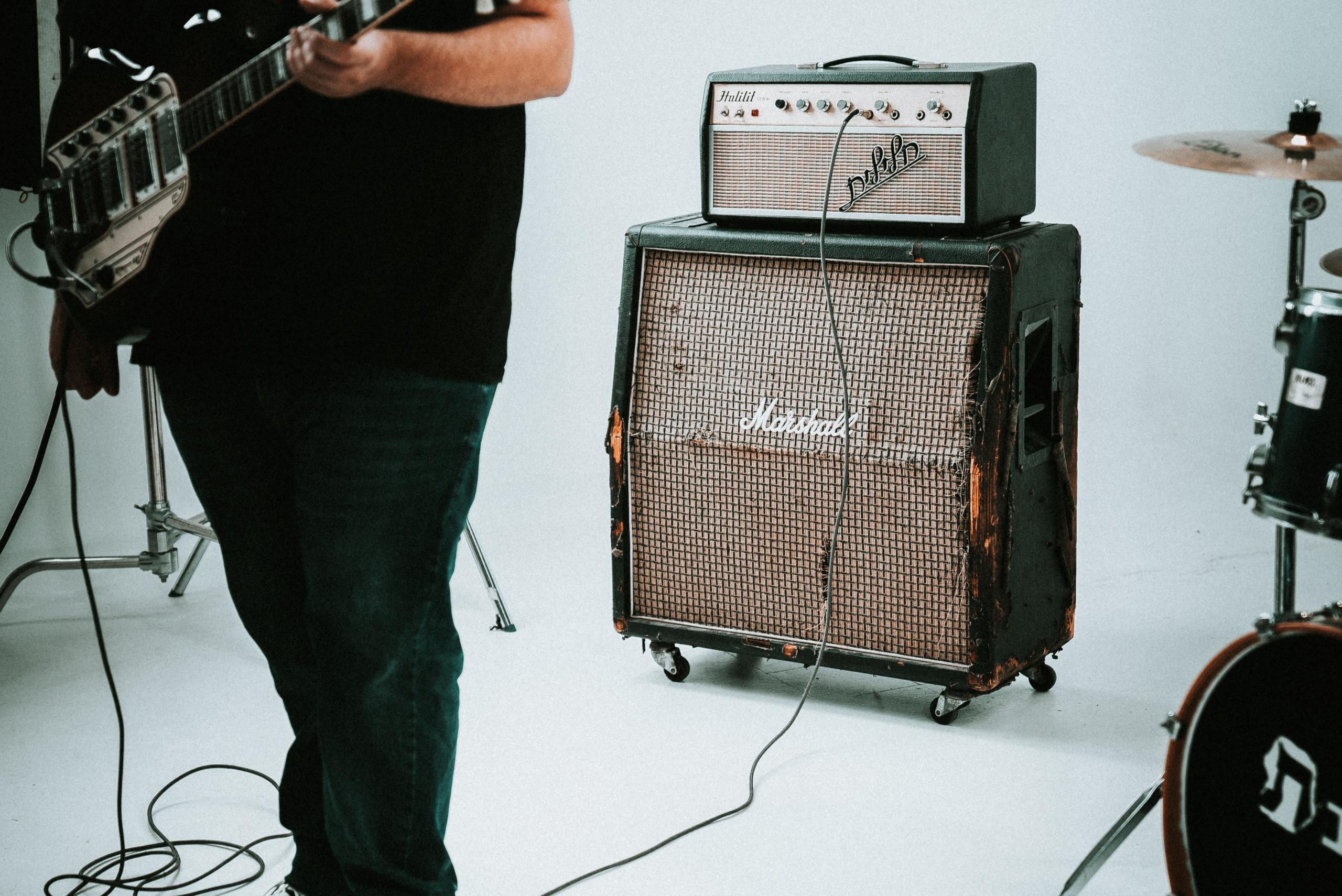 person spiller elektrisk gitar med forsterker