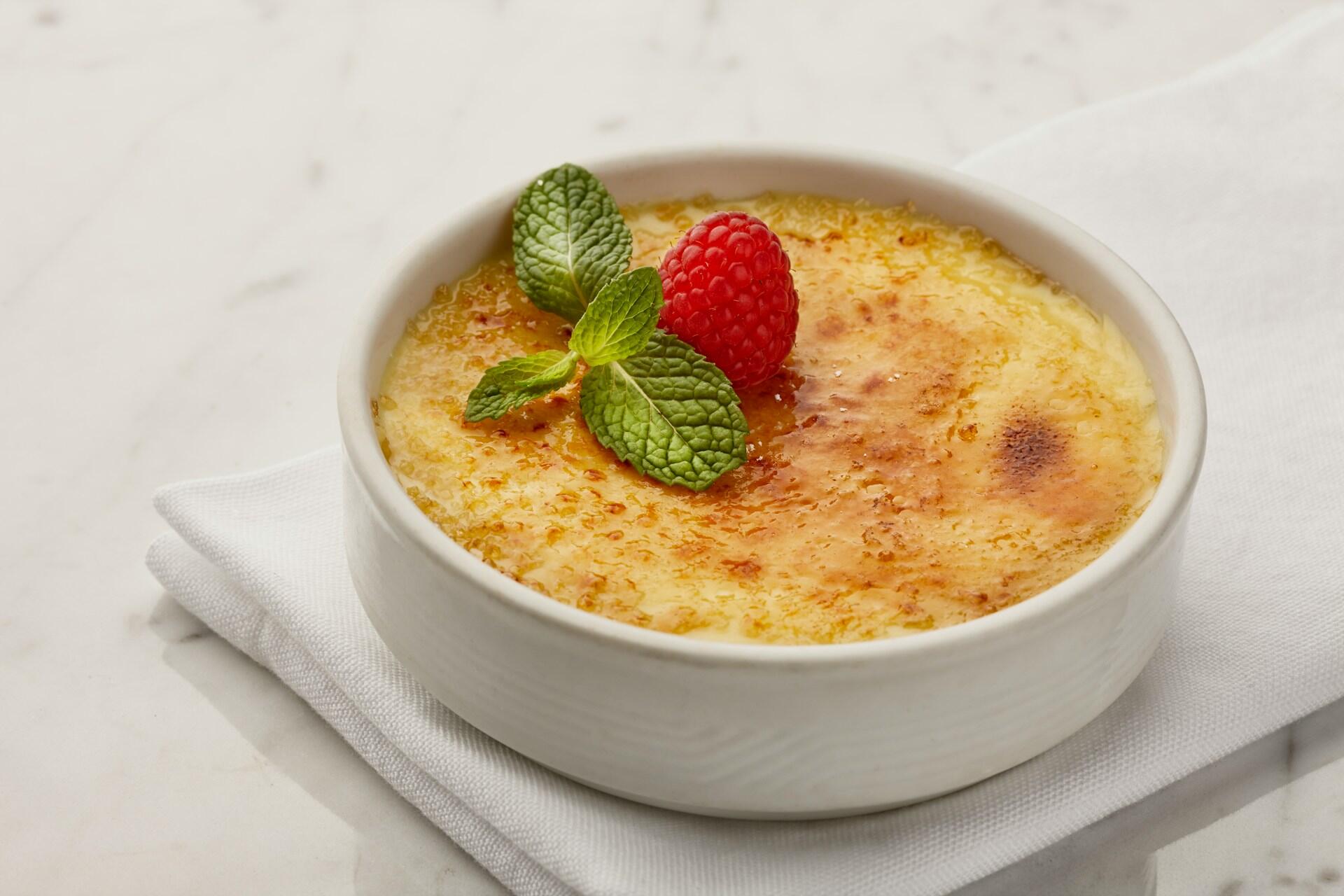 Creme brulee med bringebær og mynte på toppen.