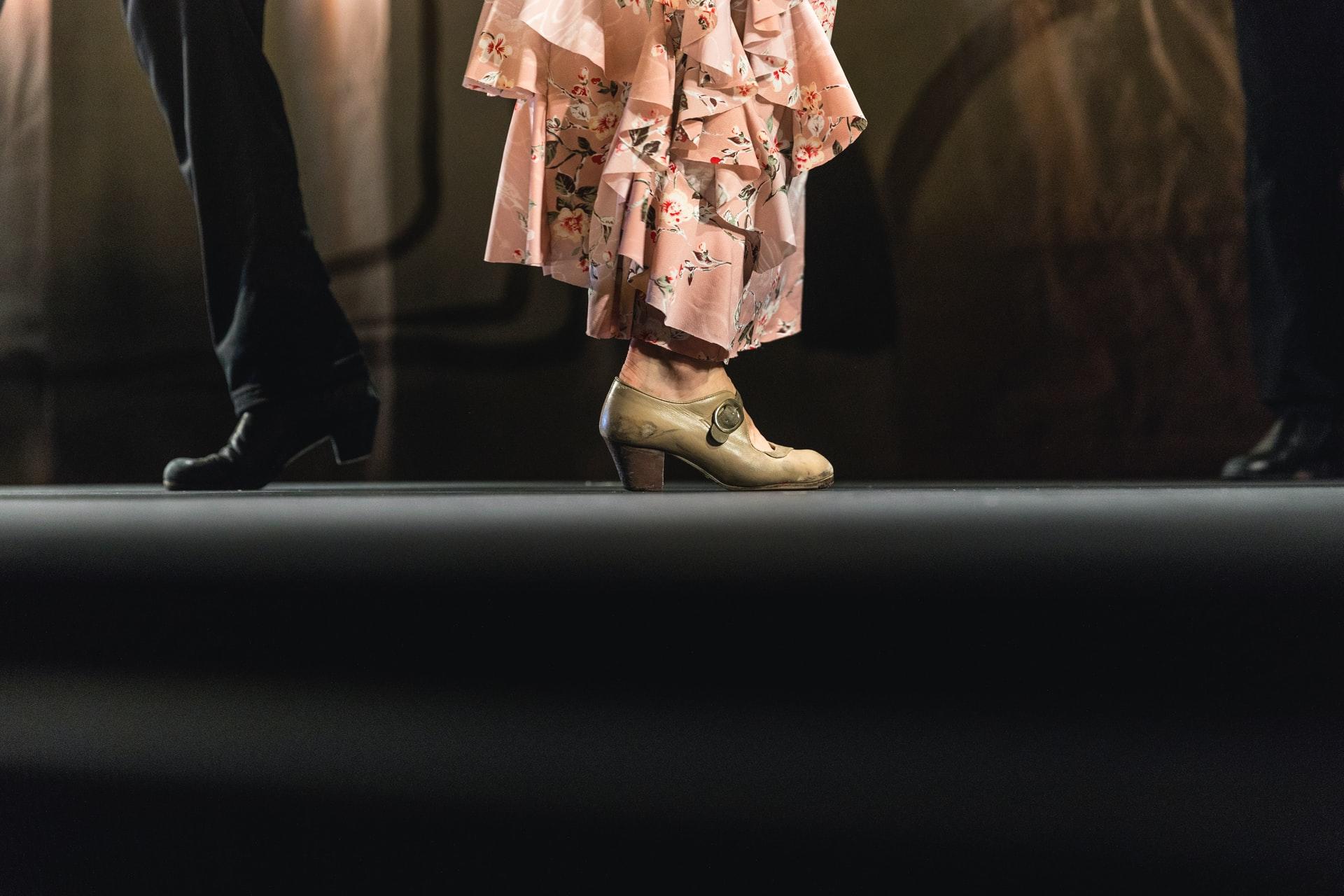 Beina til mann og kvinne med dansesko på en scene