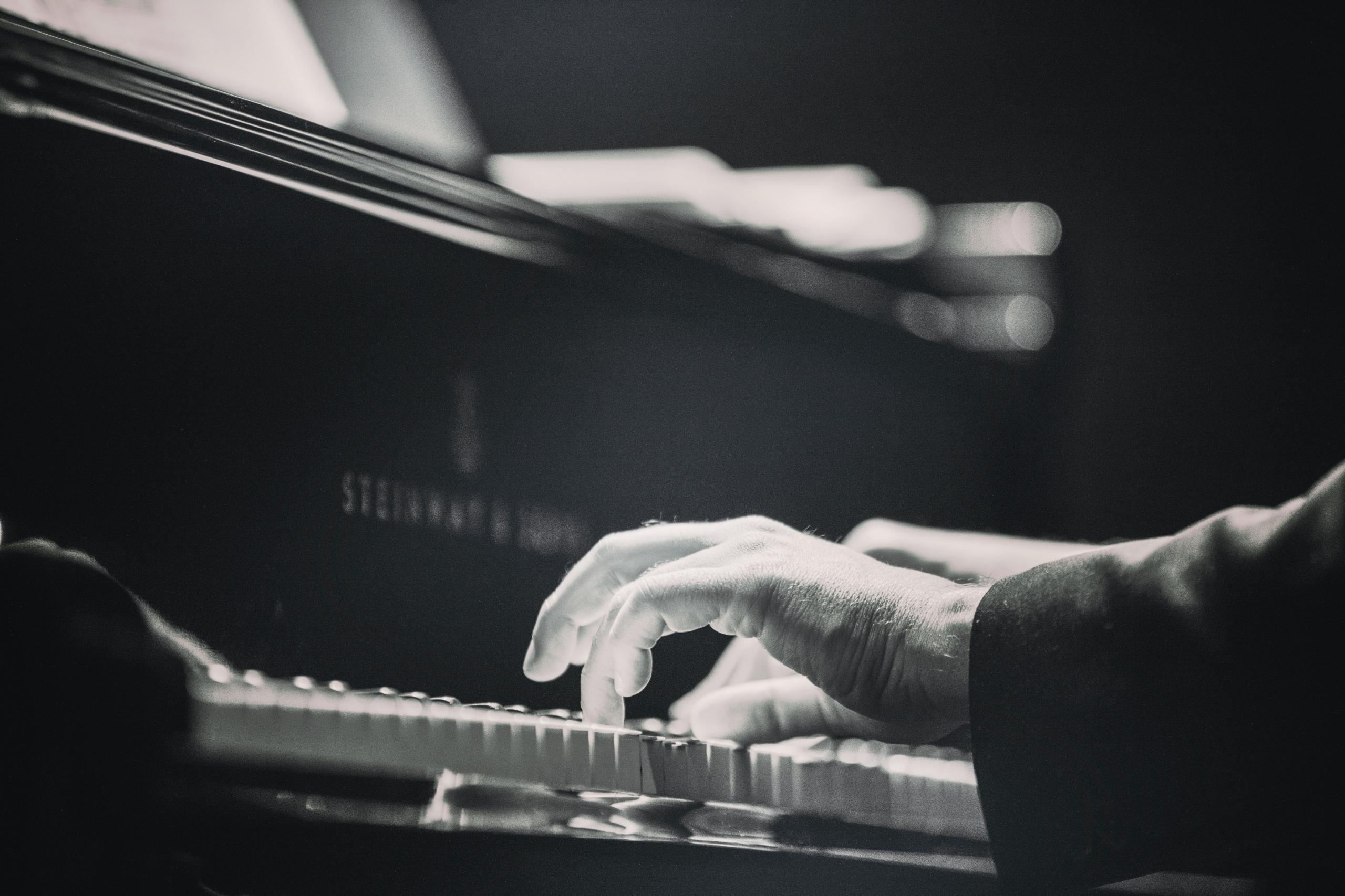 nærbilde av hender som spiller på et piano fra Steinway, det ser ut som hendene til en gammel mann