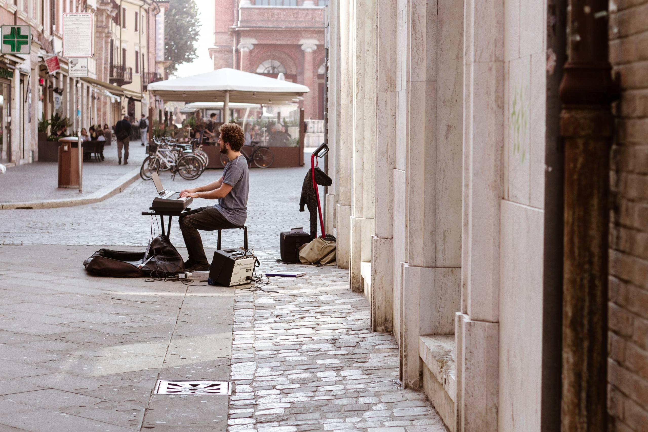 en gatemusikant sitter i en gangvei og spiller på et keyboard
