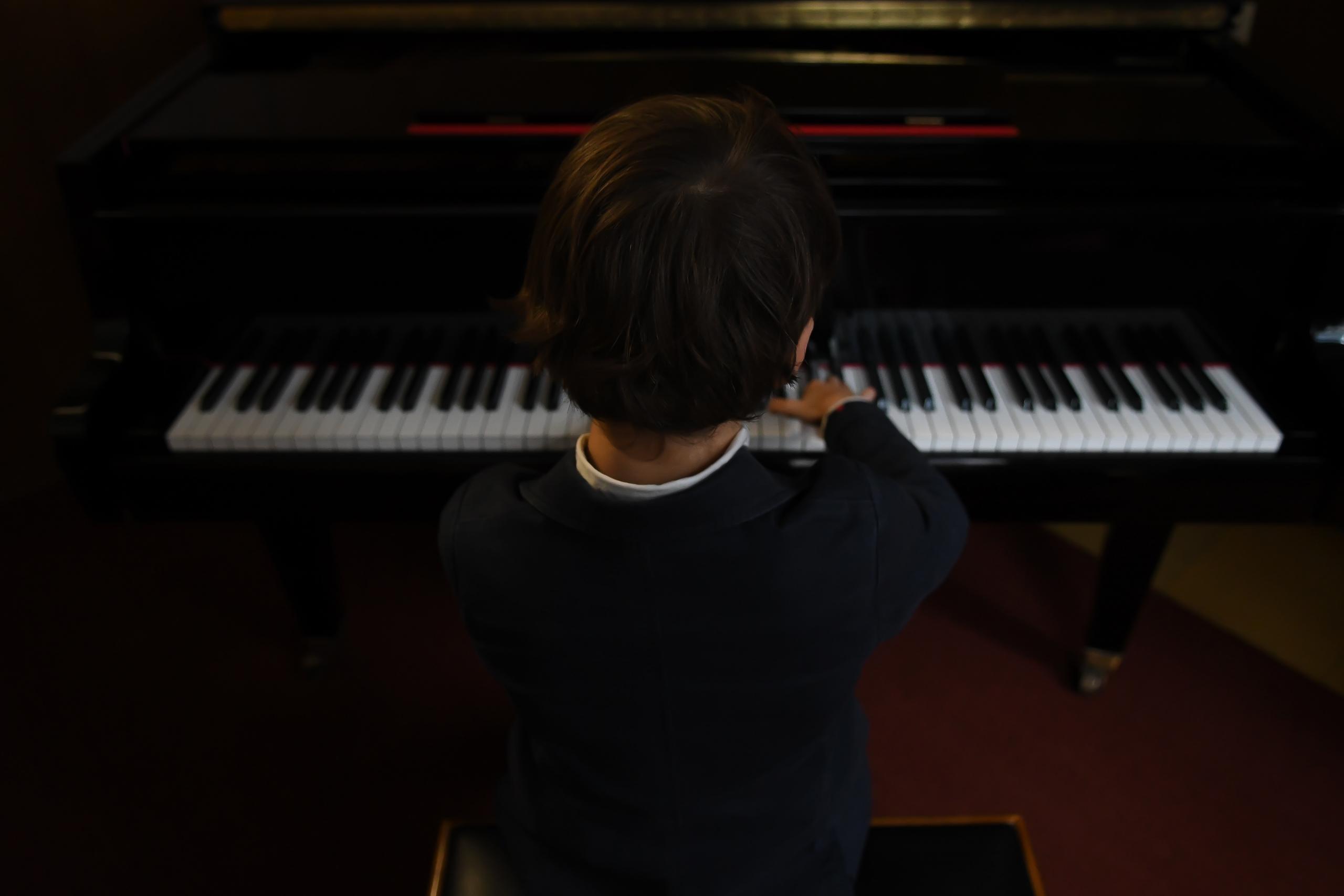 en ung gutt i kanskje 10-årsalderen sitter ved et piano
