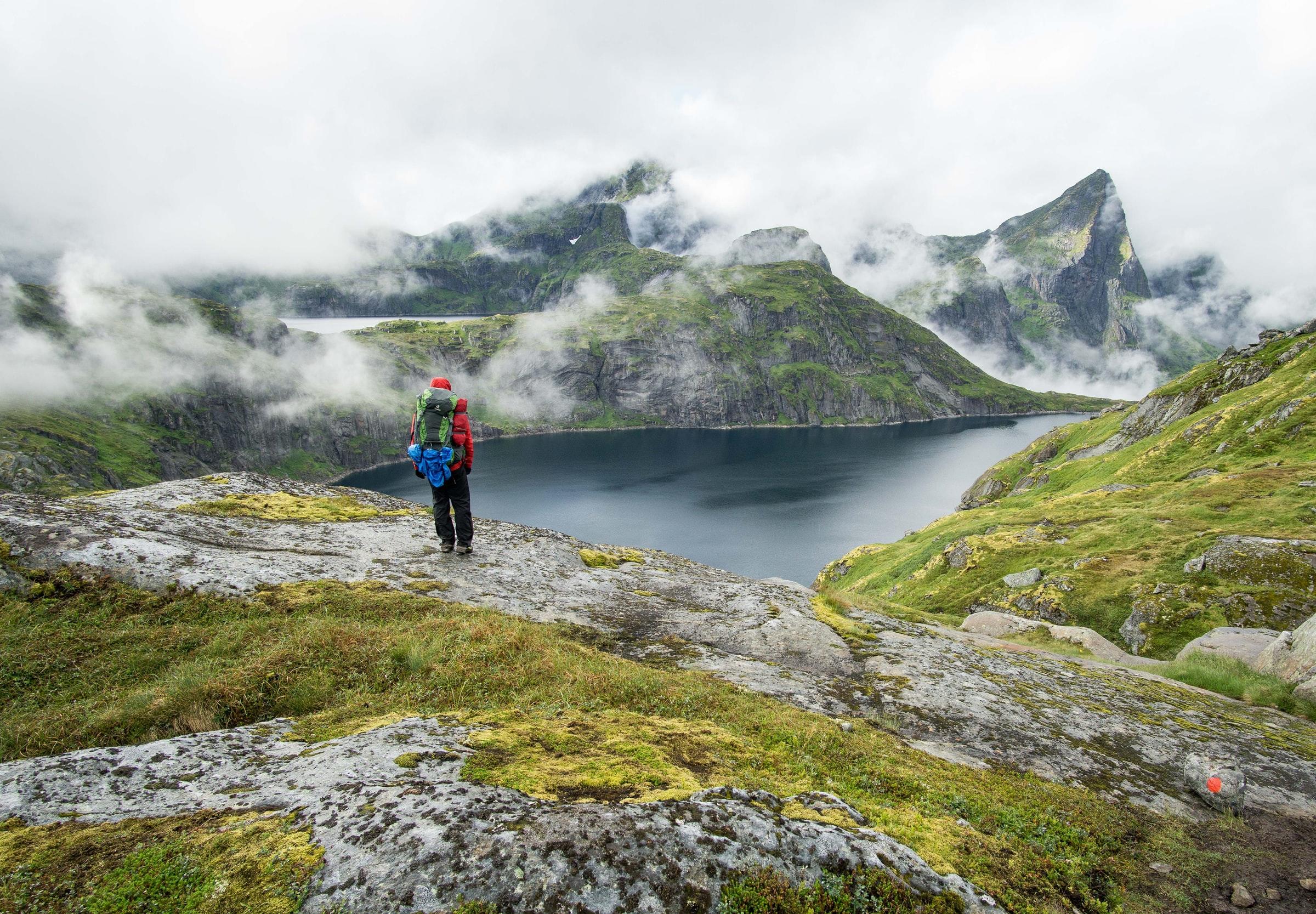 person går på tur i fjellet, skyete himmel
