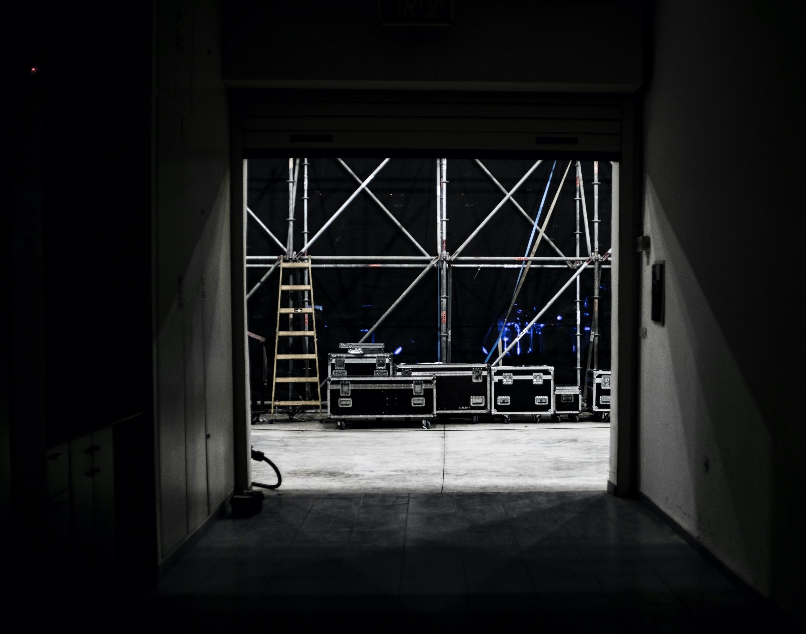et mørkt bilde av backstage med stillasaktige konstruksjoner og kasser med utstyr