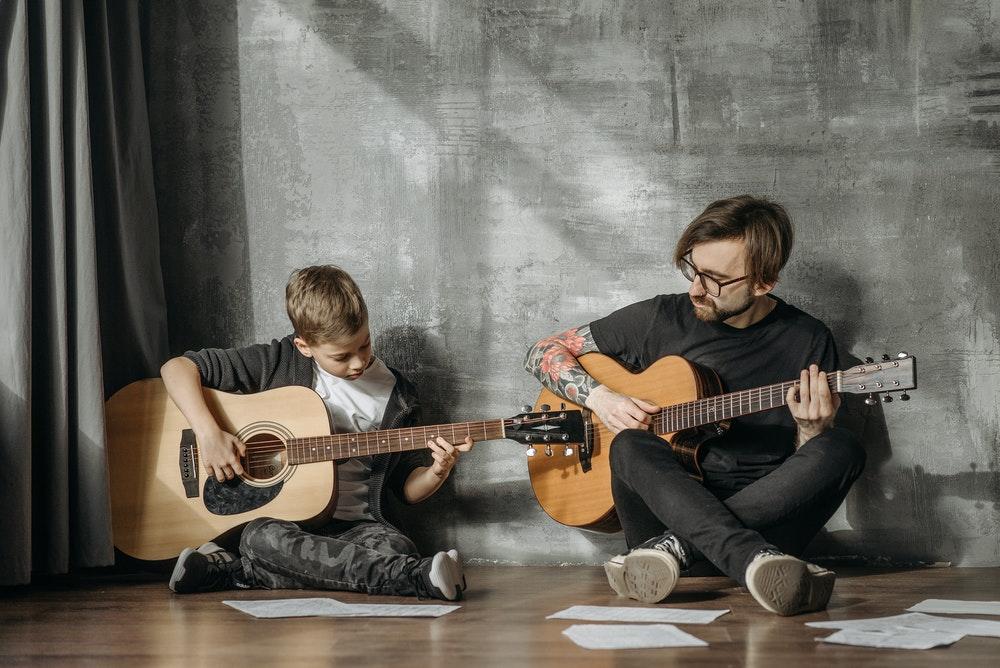 En mann som lærer en gutt å spille gitar