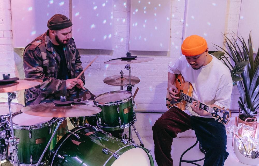 To menn som spiller trommer og gitar