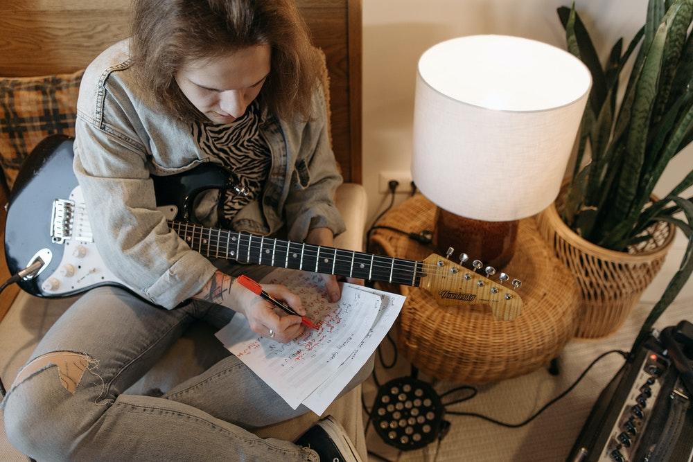 Person som spiller gitar og skriver noter