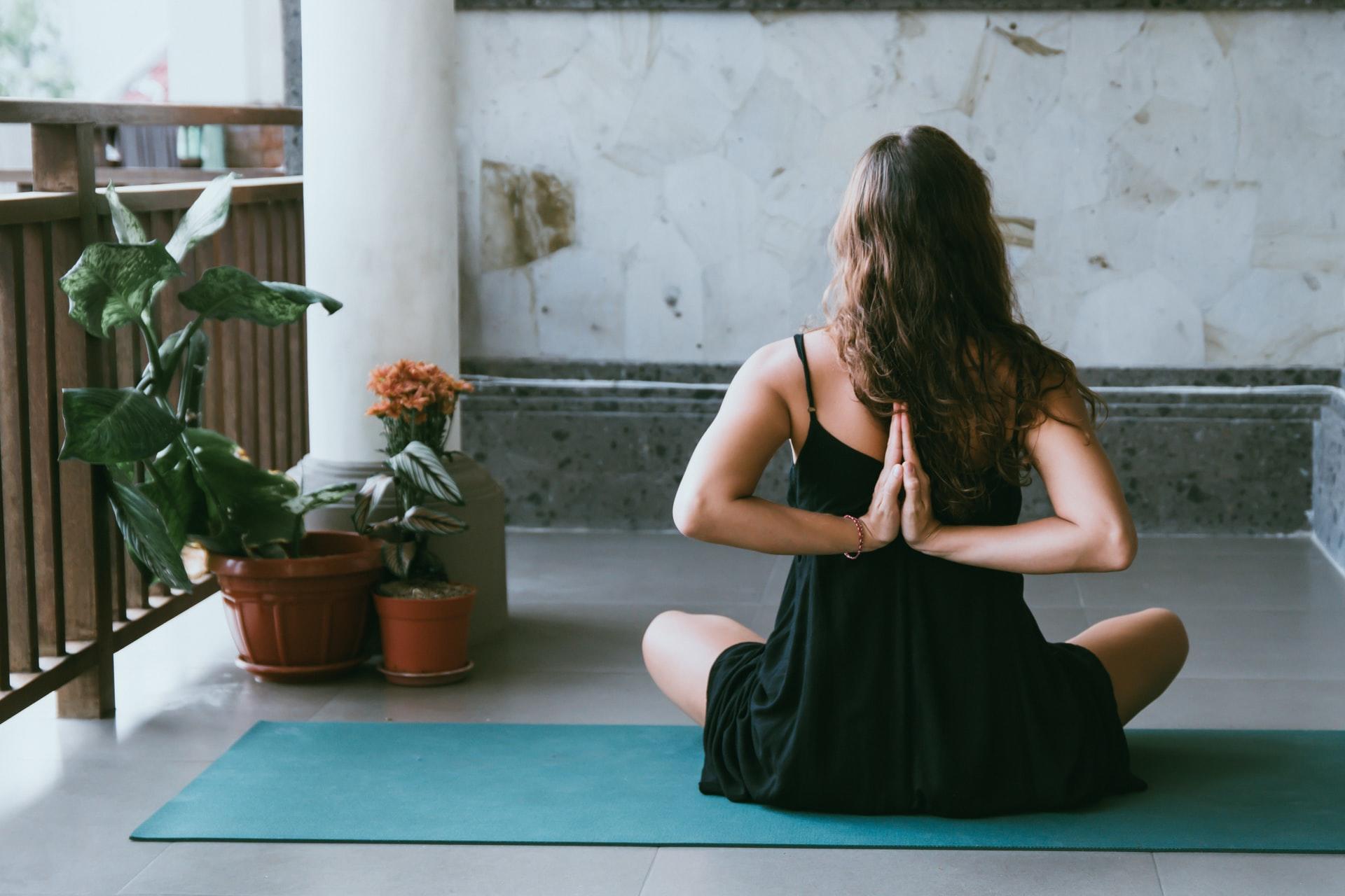 Kvinne som sitter i yogastilling på en matte ute