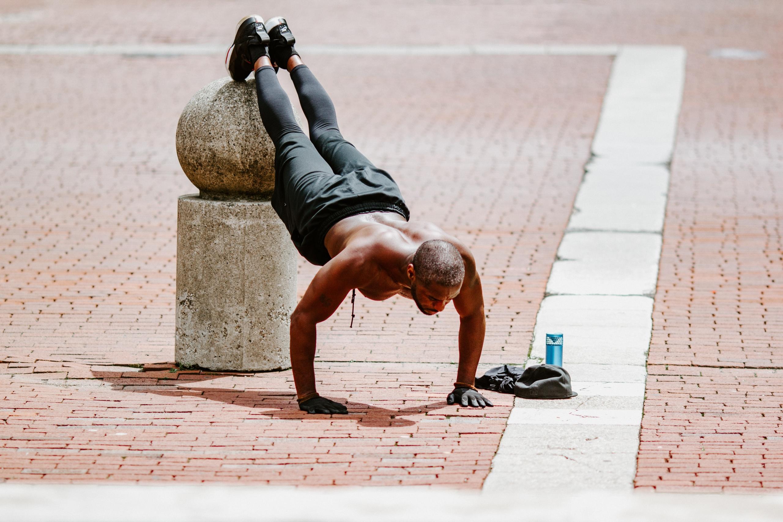 mann har plassert føttene på en sementgjenstand utendørs og tar pushups med kroppen i en diagonal posisjon